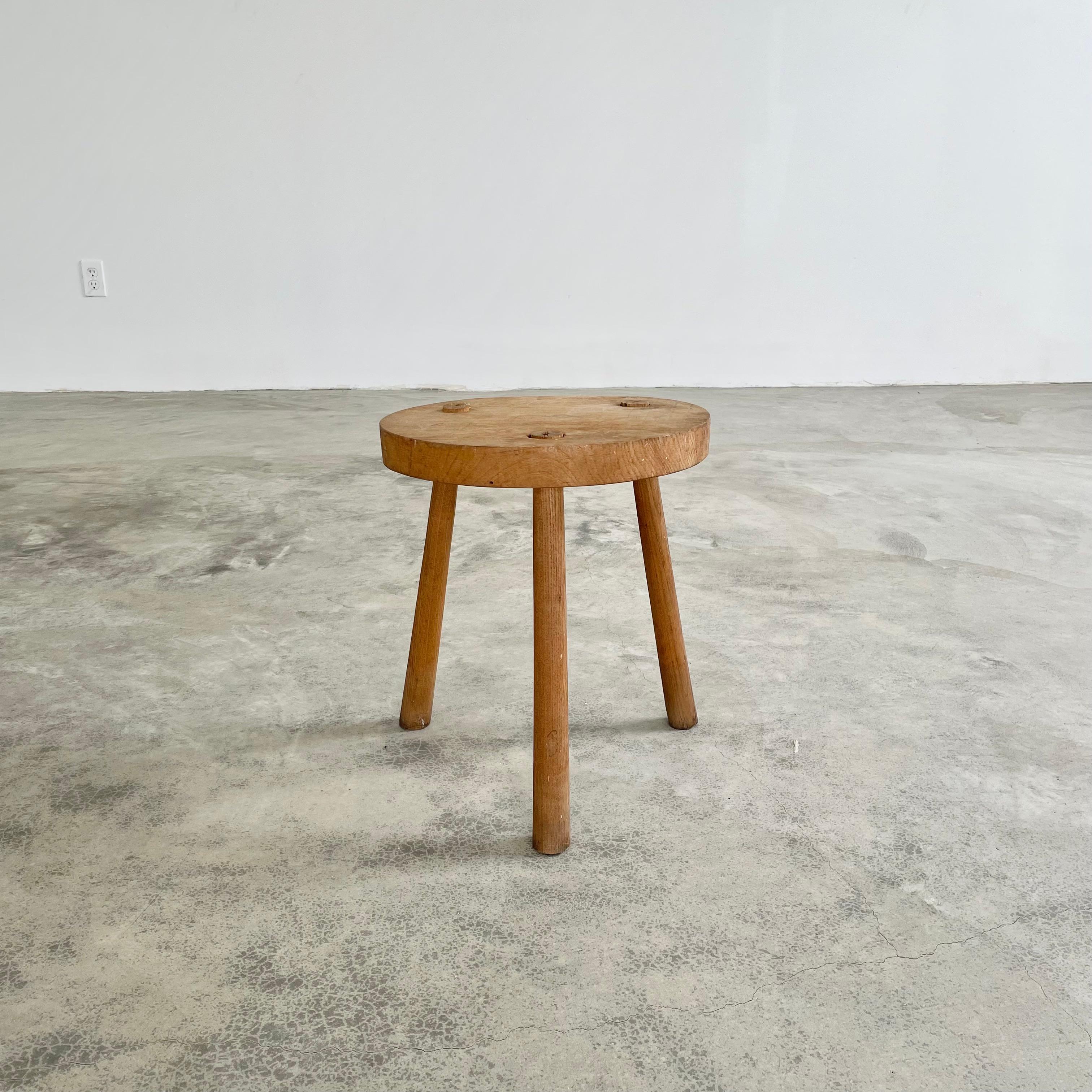 Vintage wooden stool made in France, circa 1960s. Thick round seat and substantial tripod legs that taper getting wider towards the base. Great lines and shape with a very sturdy build. Age, patina and wear as shown.