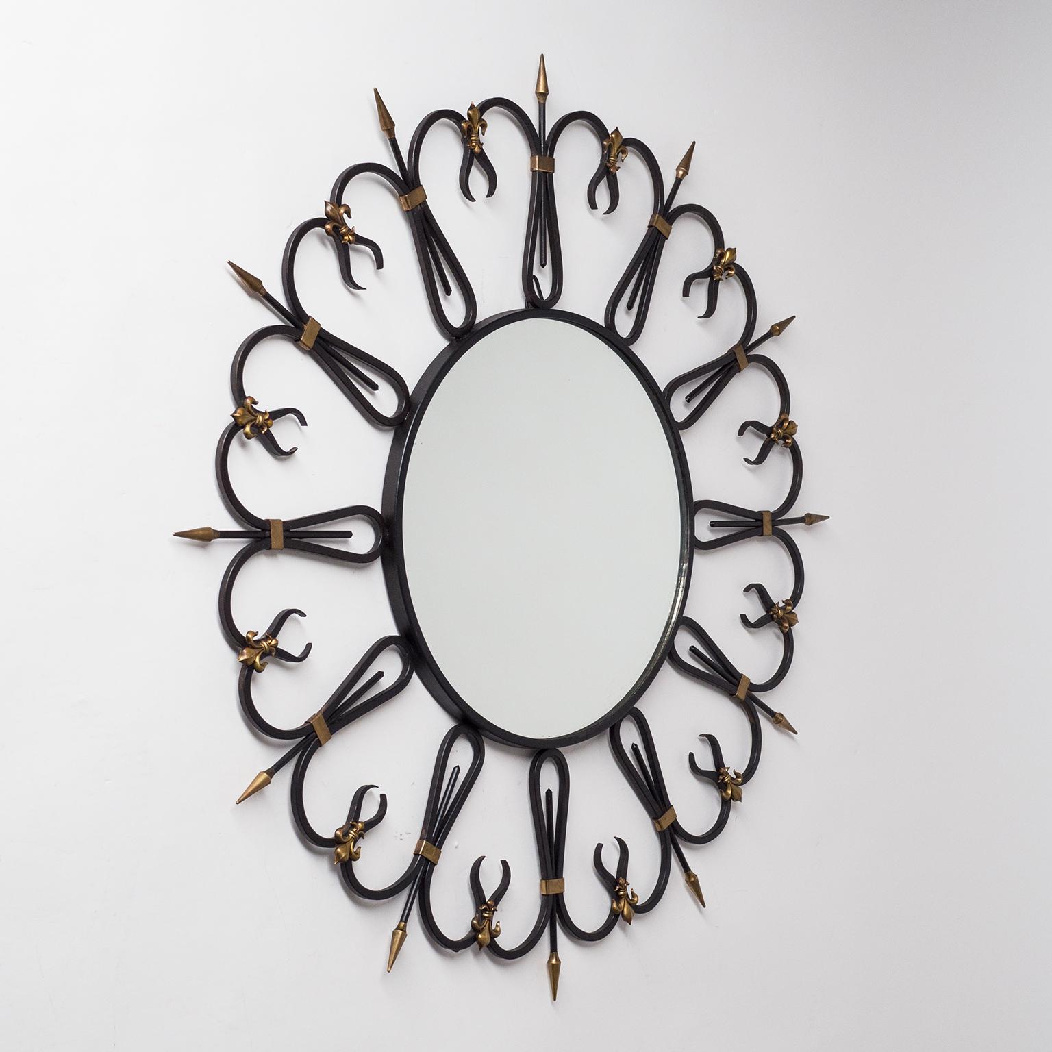 Rare miroir en fer forgé français avec des détails en laiton des années 1950. Fer très joliment travaillé, laqué noir, avec embouts en laiton et décorations Fleur de Lys. Bon état d'origine avec un peu de patine. Mesures : Le diamètre du miroir est