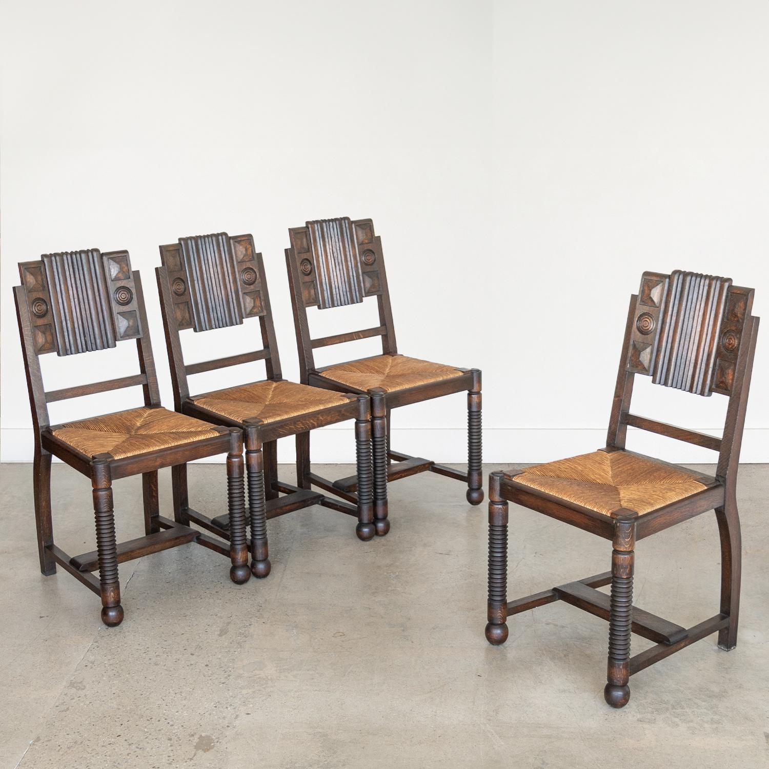 Great set of four wood and woven chairs by Charles Dudouyt from France, 1940's. Carved legs with beautiful carved wood design on backs. Original woven rush seats in great vintage condition. Original dark wood finish is in vintage condition with some