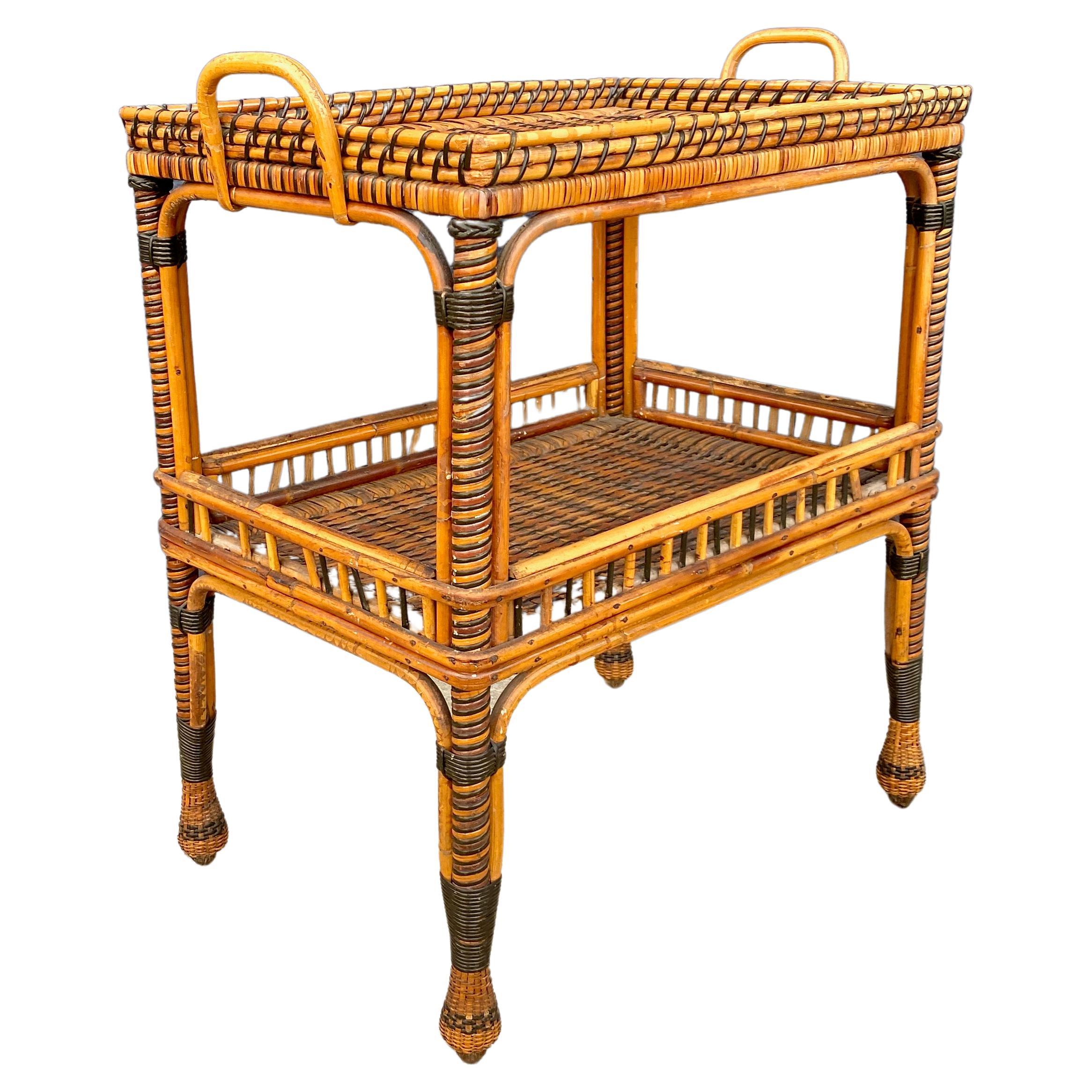 This a beautifully graphic c. 1930's French woven rattan side table. The table features a fixed tray top surface with a coordinating lower shelf. The choice to use both a natural and an ebonized reed in the weaving makes this table a great