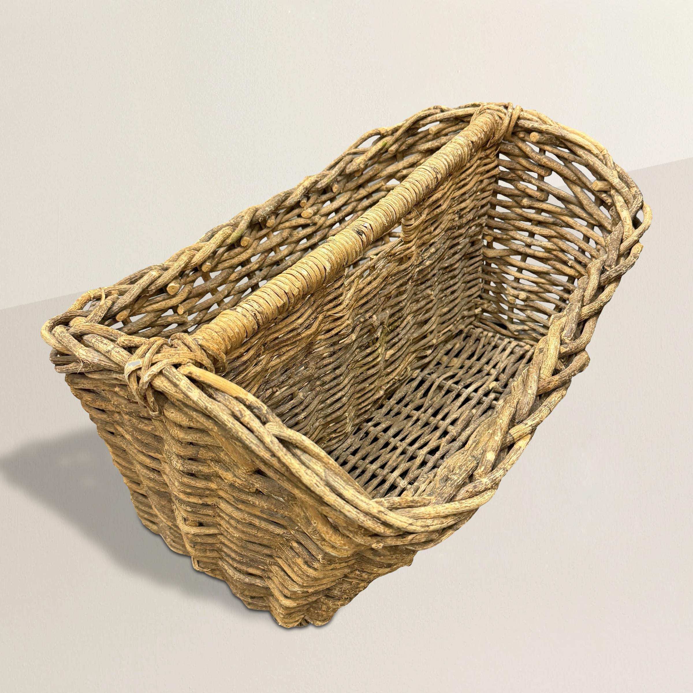 This charming 20th-century French hand-woven wicker garden trug exudes rustic elegance and practicality. Designed with two sections divided by a sturdy handle in the center, this trug was originally used for carrying tools, plants and freshly cut