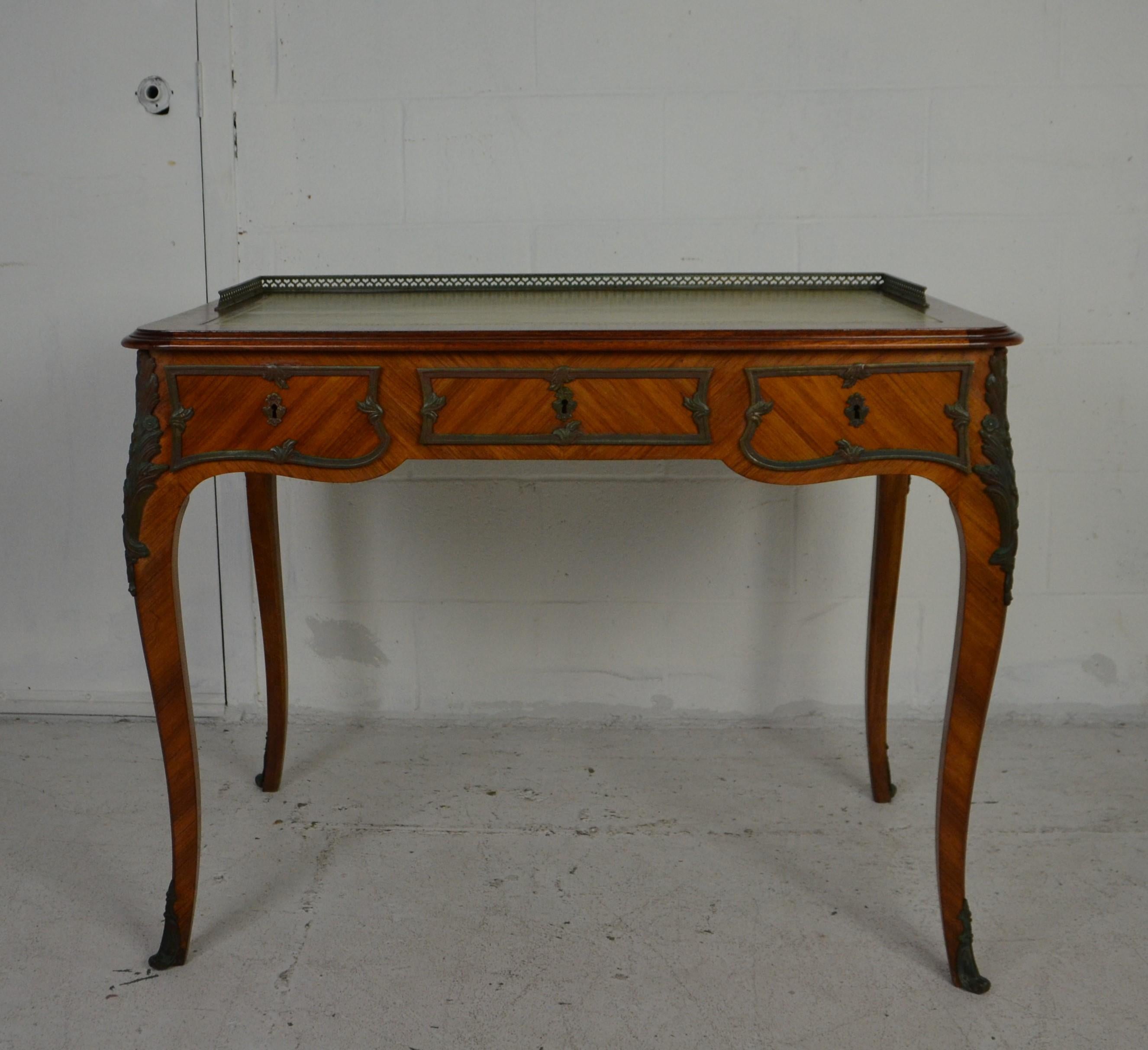 A genuine French Louis XV style desk / bureau plat in a small size. Ideal for a ladies desk. King-wood with 3 drawers and featuring a fretwork brass gallery to the top. Inset with tooled leather top. Decorated with bronze around the drawers, legs