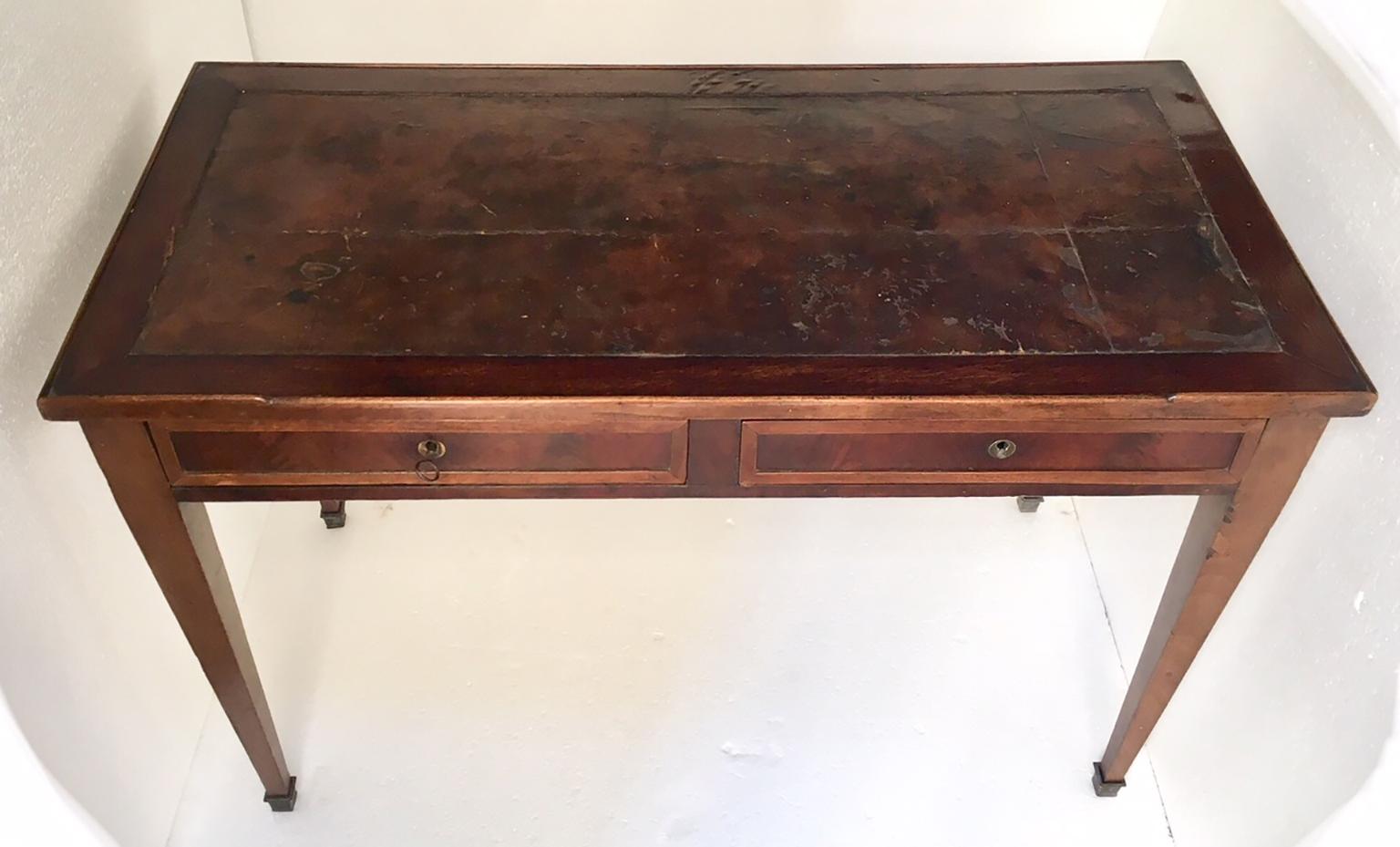 Simple and elegant French writing desk, in Louis XVI style, made of mahogany palm wood, with the original leather top, has two drawers and the legs end in brass sabot