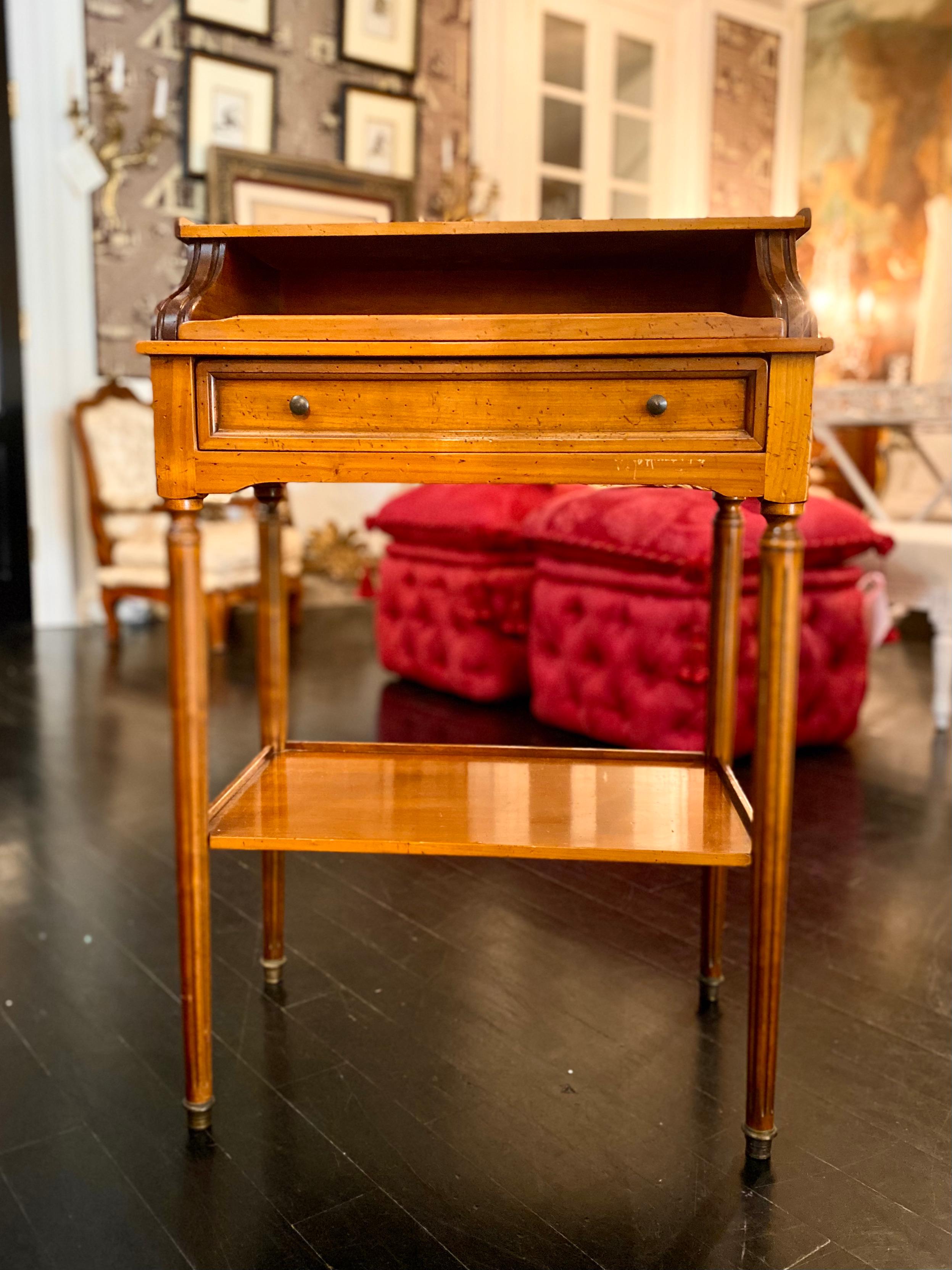 French writing table on casters, pull-out gilt-tooled leather top above a drawer, two storage shelves. Versatile in its design and size, beautiful golden colour with black leather writing surface detailed in gilt.