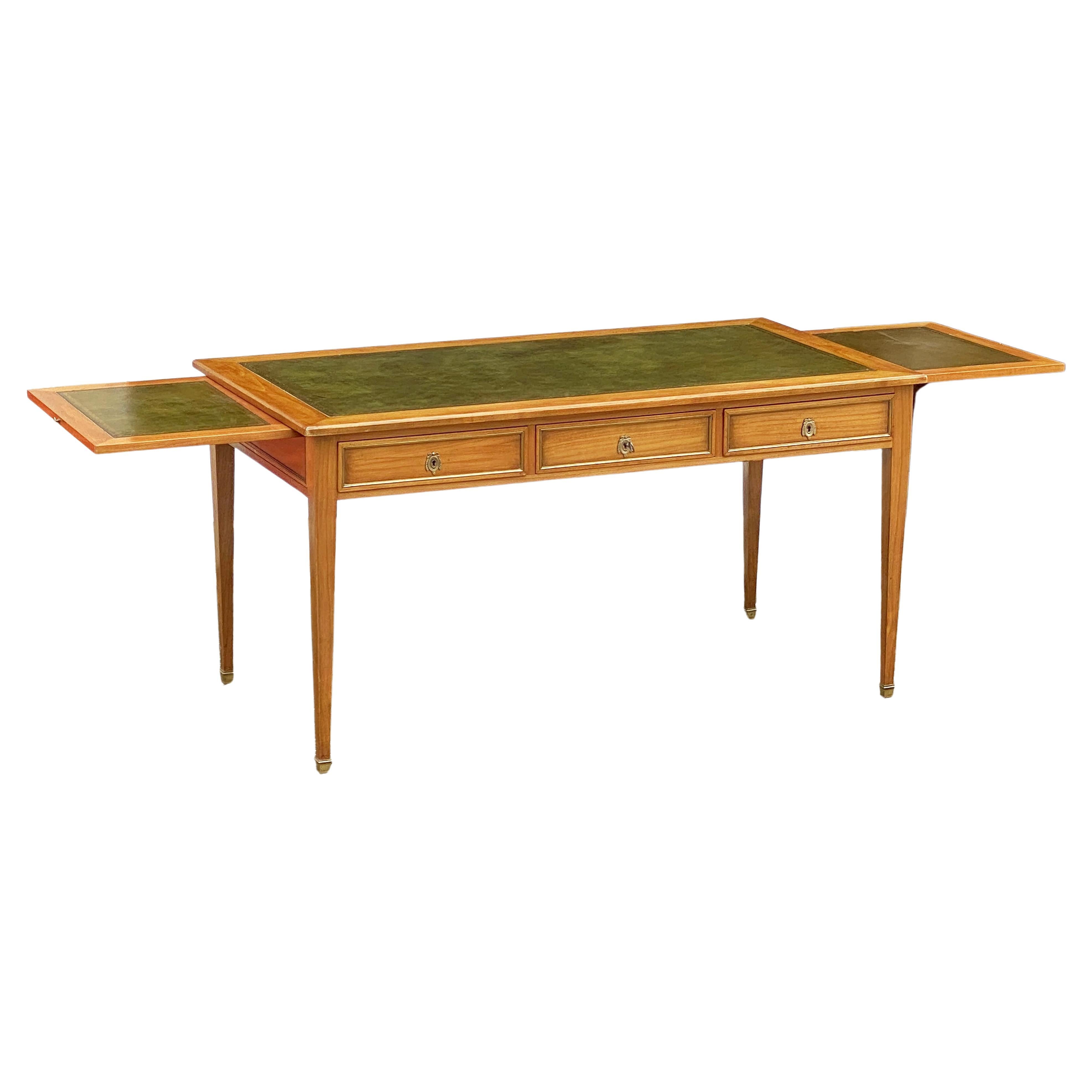  A fine French writing table or desk of patinated and polished cherry-wood from the late 19th century, featuring a beautiful embossed green leather top over a frieze of three drawers - each drawer with an elegant brass edge surround. 
The back