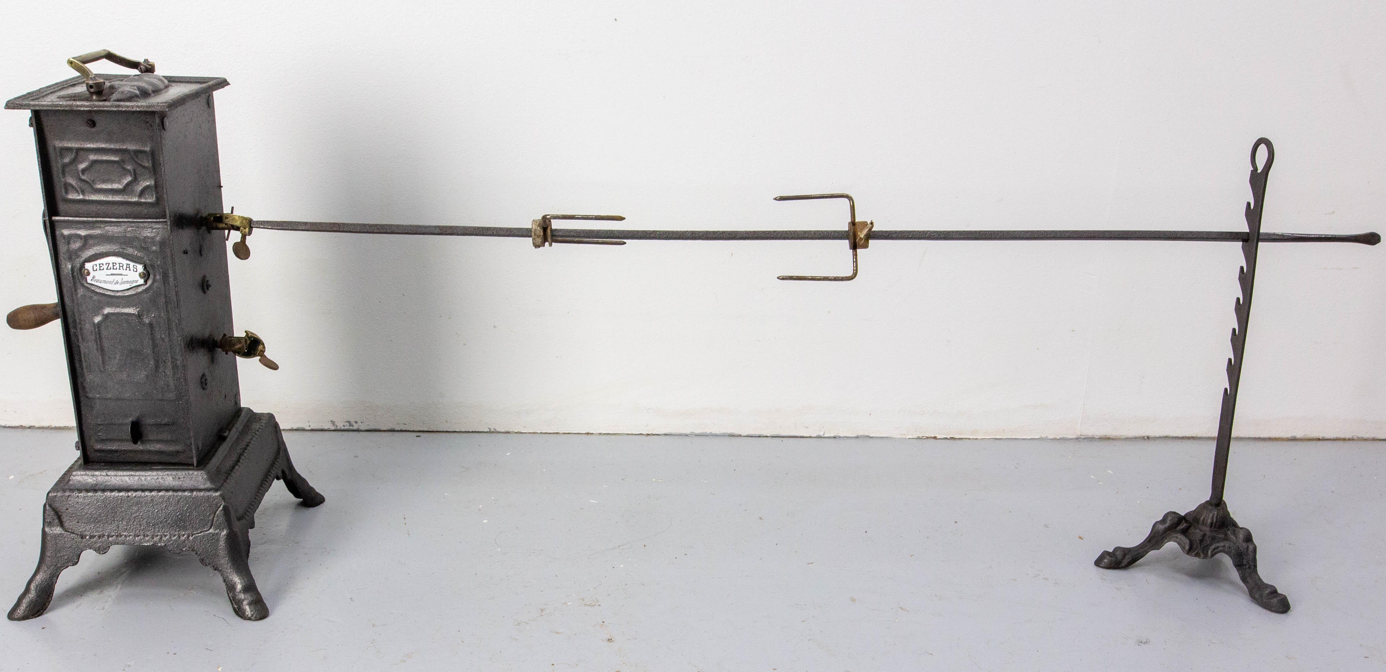 Ornate and functional 19th-century French cast-iron rotisserie.
It consists of a winding jack resting on four claw feet, a handle, a winding key, 2 positions for the spit from the rotisserie, a cast-iron tripod spit with 7 spit hooks and a ring on