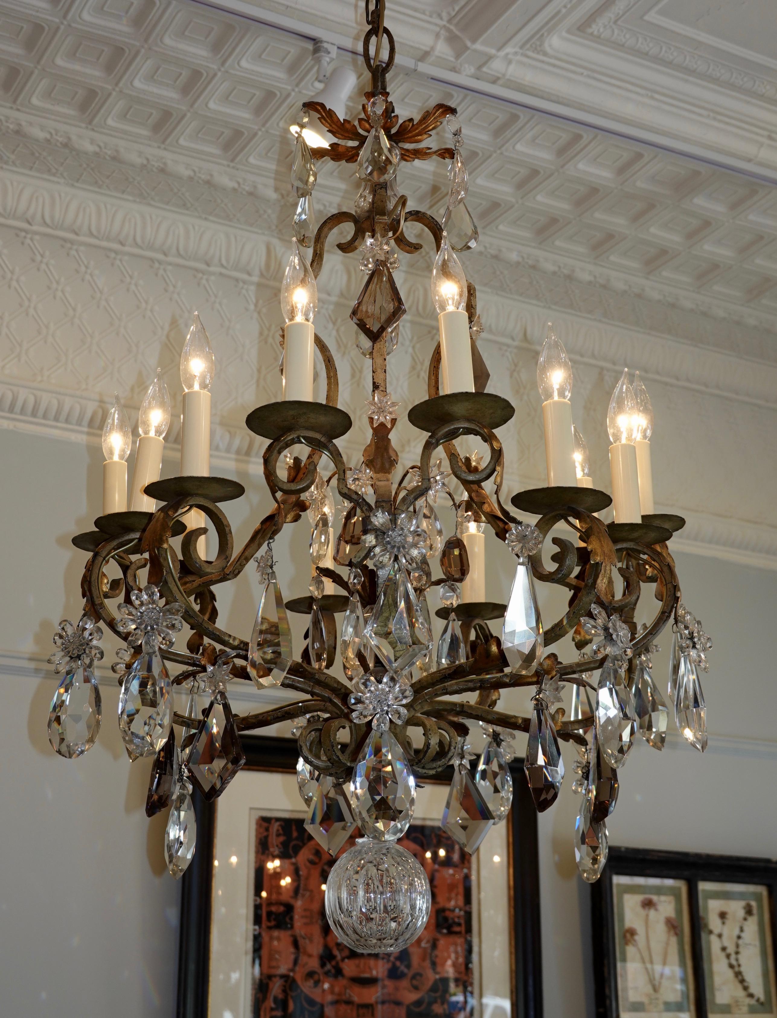 Un grande lampadario francese a gabbia in ferro battuto e cristallo di alta qualità, ricablato per gli Stati Uniti con 12 luci. Il lampadario è caratterizzato da pesanti cristalli tagliati, alcuni di colore ametista o fumo, fiori di cristallo