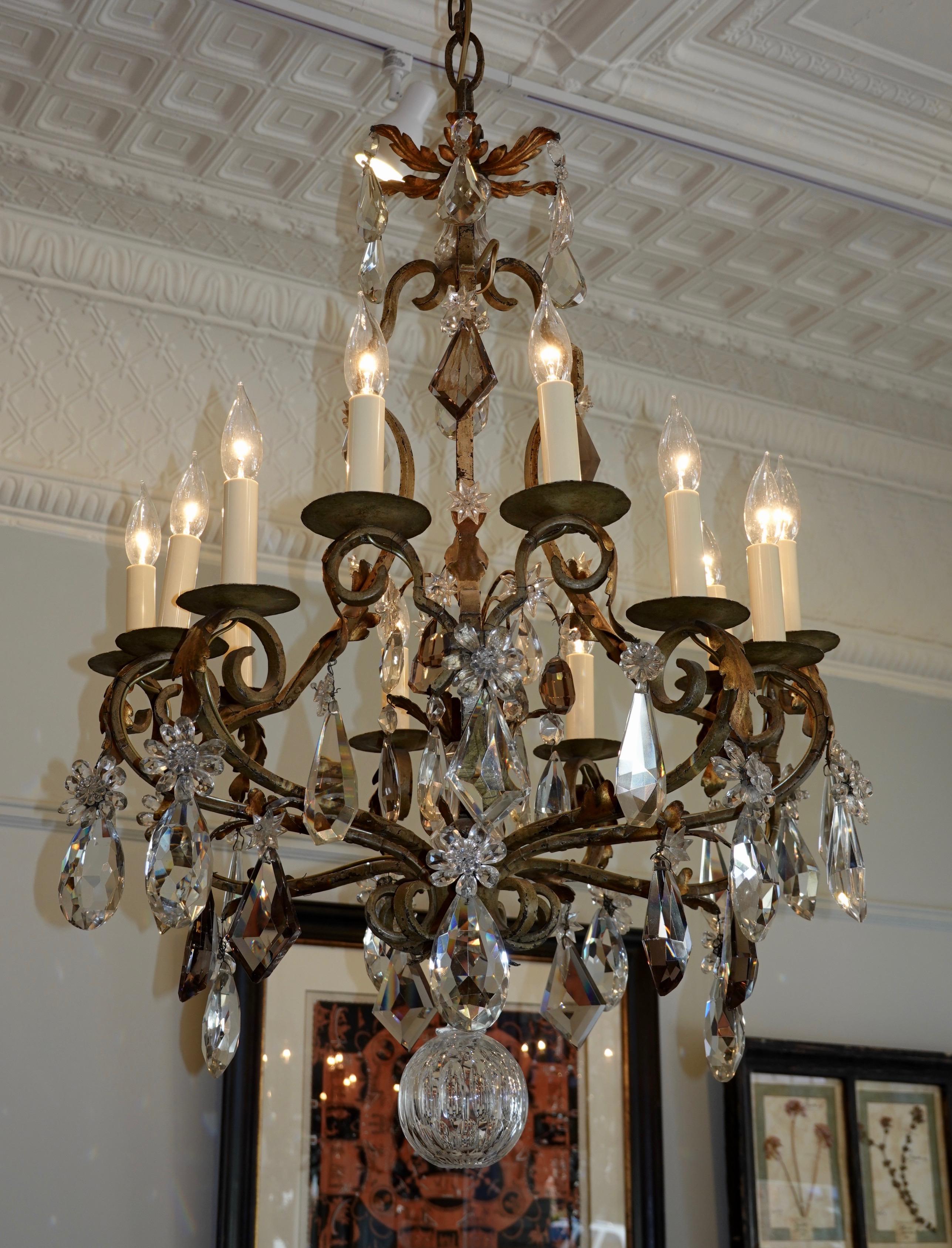 A large, high-quality French cage-form wrought iron and crystal chandelier, rewired for US with 12-light. The chandelier features heavy cut crystals, some light amethyst or smoke colored, hand-strung crystal flowers, a central spray in the interior,