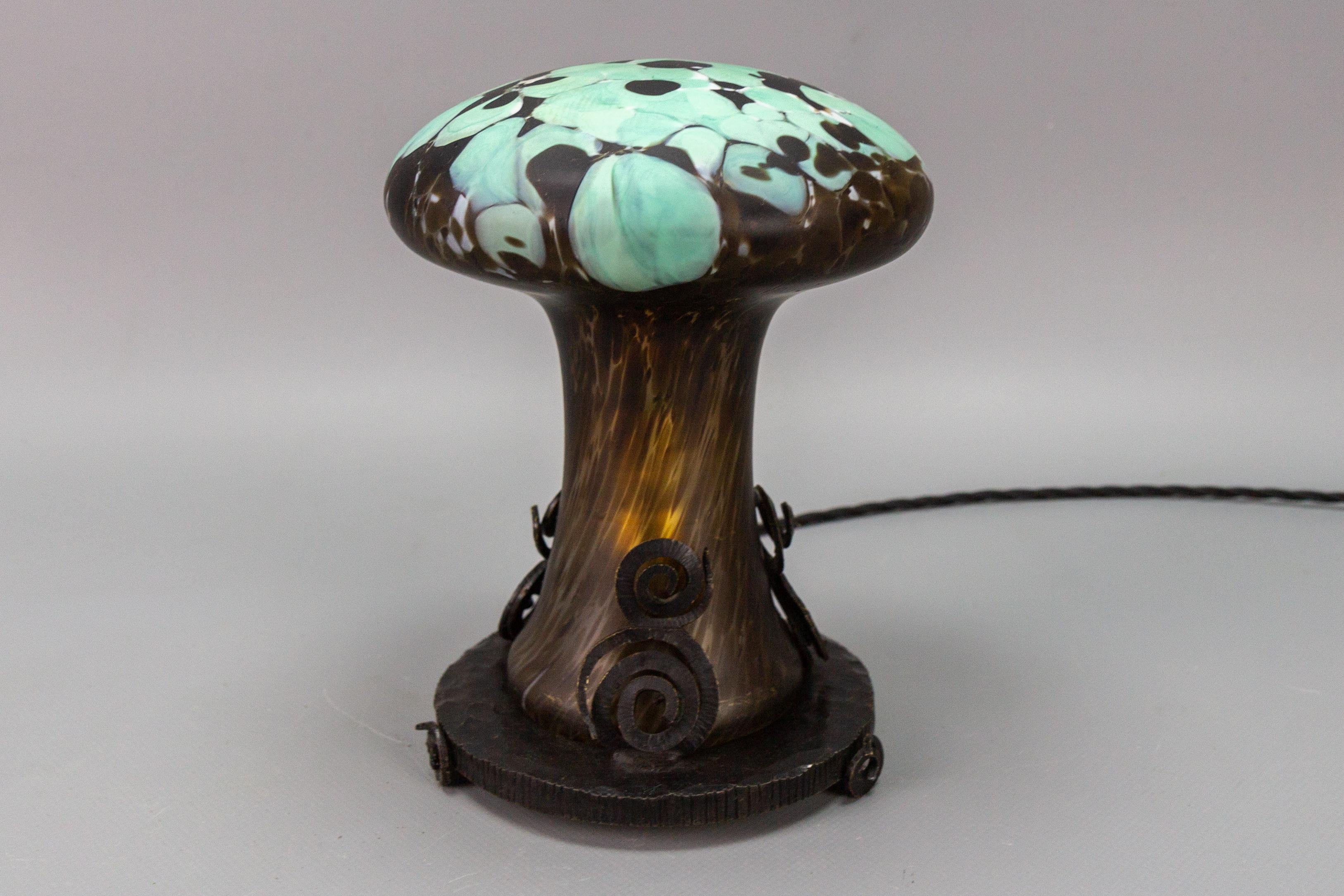 French Art Deco style Wrought Iron and art glass table lamp in the shape of a mushroom, circa the 1950s.
An adorable and cute Art Deco style wrought iron base table lamp with light turquoise and dark brown color mushroom-shaped art glass body. The