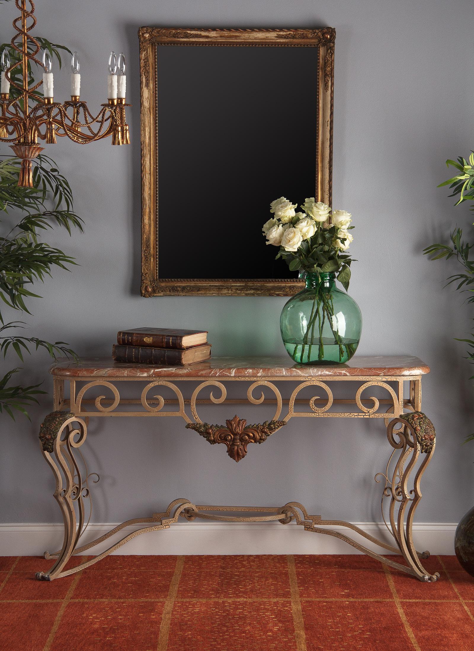 An elaborate vintage wrought iron and marble console table, French, circa 1950. The ornate wrought iron base is loaded with scrollwork. Each of the four legs consists of two thick bowed scrolls accented by sets of slim inner scrolls, all joined by