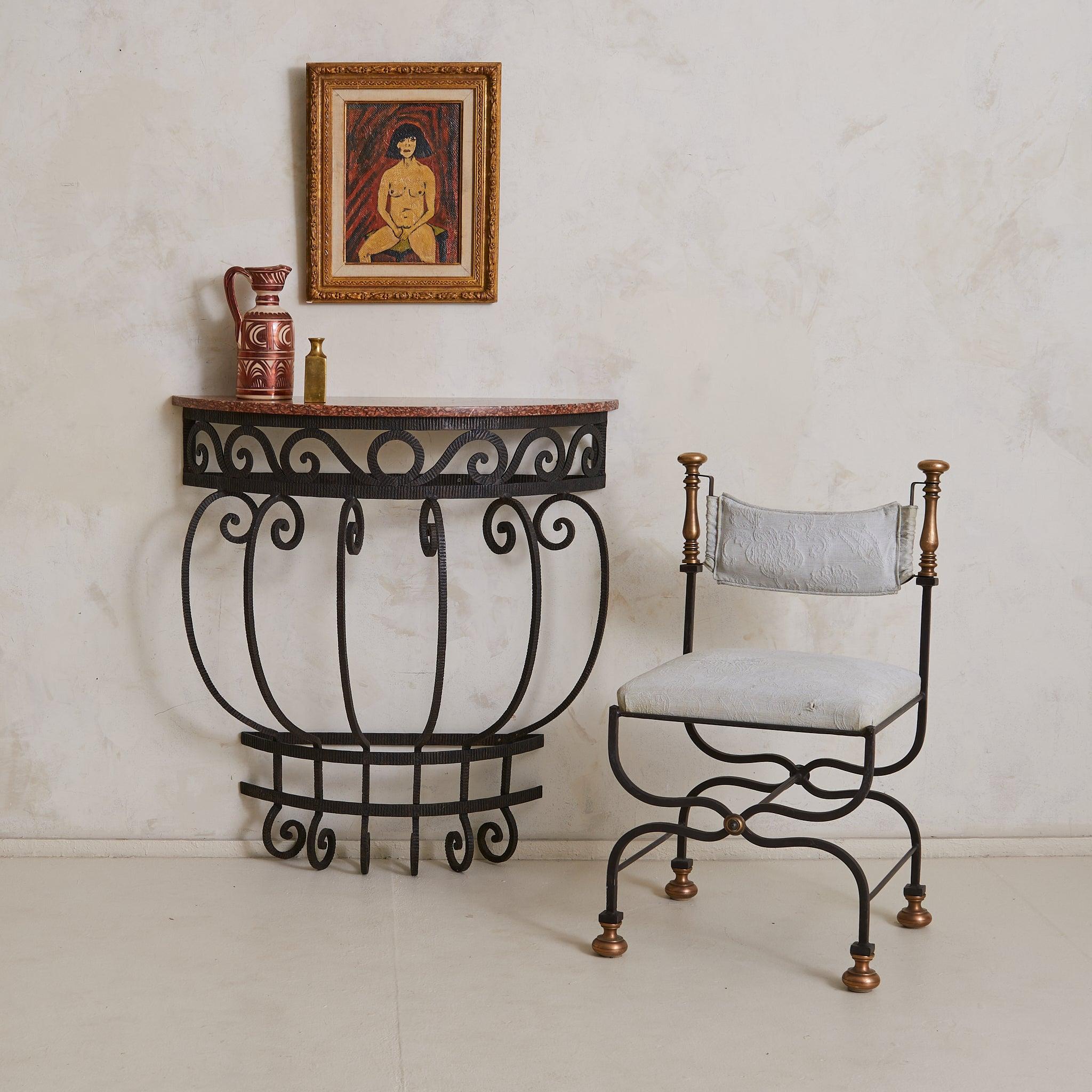 Hand-forged in France in the 1940's this half-moon console pairs sculptural ironwork with a warm Rosso Verona marble top. The iron frame mounts neatly to the wall and shows a gentle pattern of scrolls—detailed enough to feel special, understated