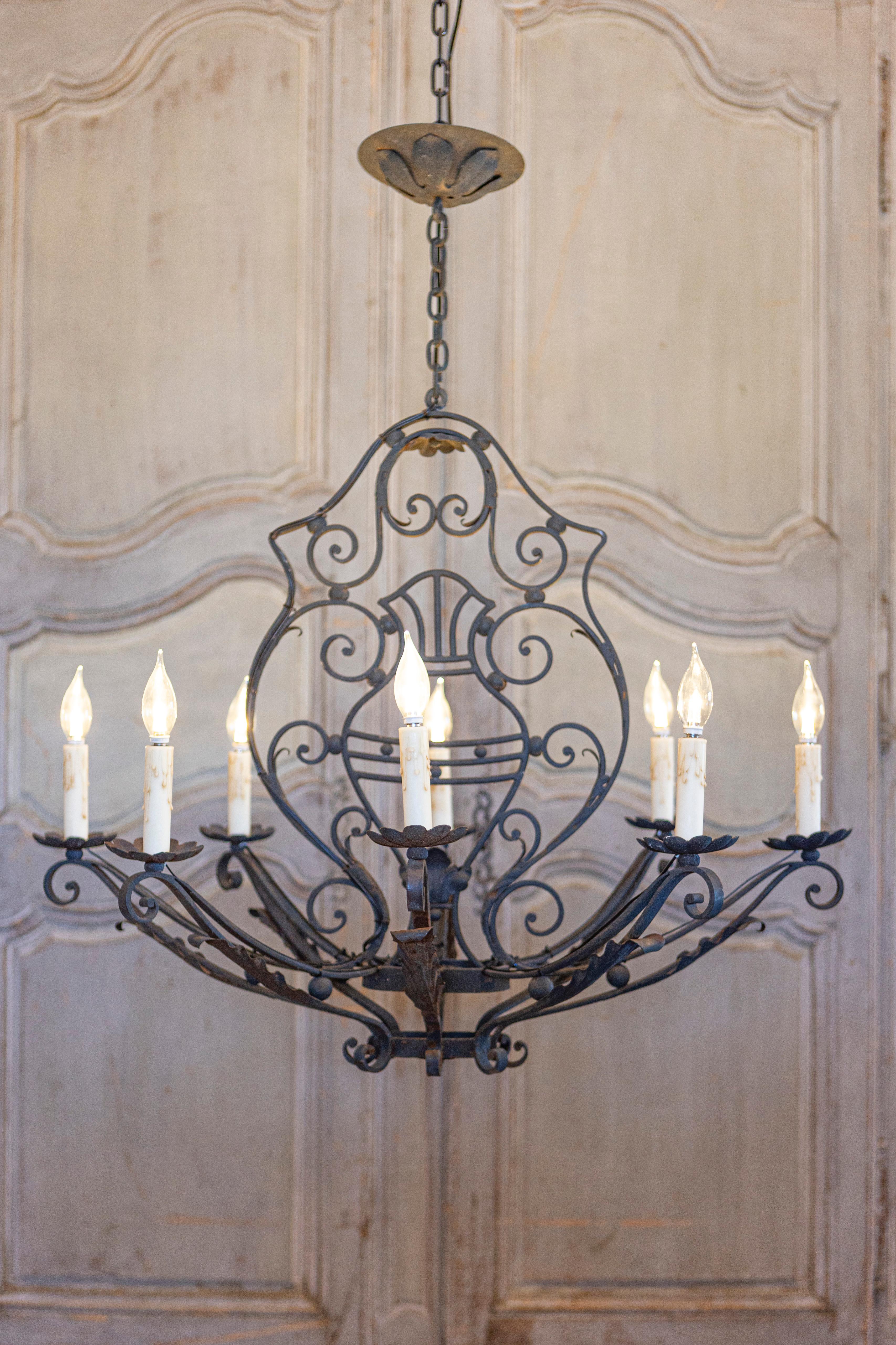 Lustre à huit lumières en fer forgé français du XXe siècle, avec des motifs de volutes et de feuilles d'acanthe. Ce lustre français en fer forgé à huit lumières présente une série de gracieux motifs en volutes, chacun orné de délicates feuilles