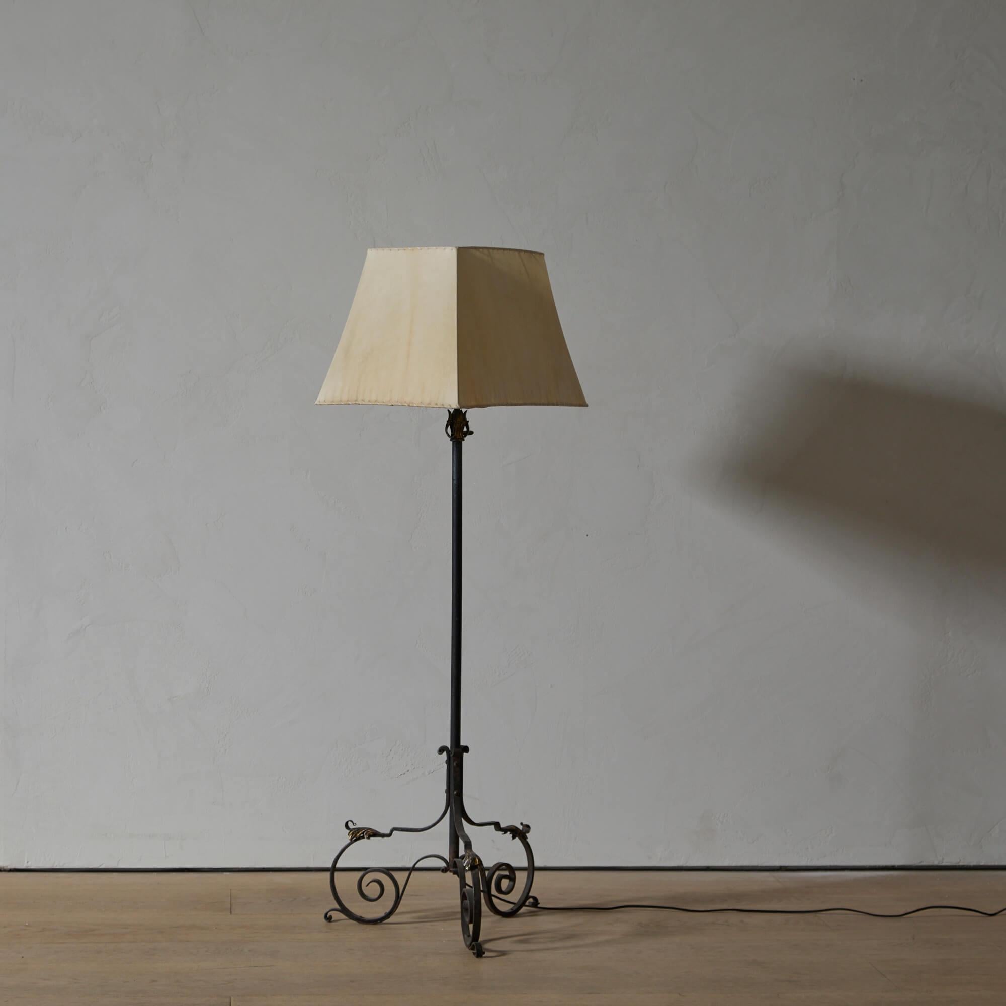 A tripod, adjustable wrought iron floor lamp, the foliate ornamentation with remnants of gilding.

Paper shade available upon request. Re-wired for use in the U.S.