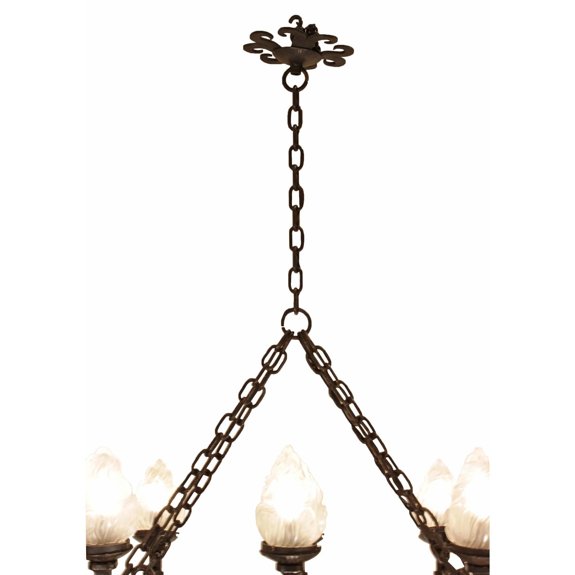 A very attractive French turn of the century wrought iron ten-light chandelier. The chandelier has an oval wrought iron base with scrolled arms that hold a twisted wrought iron flame designed light with frosted cover. The chandelier is joined to the