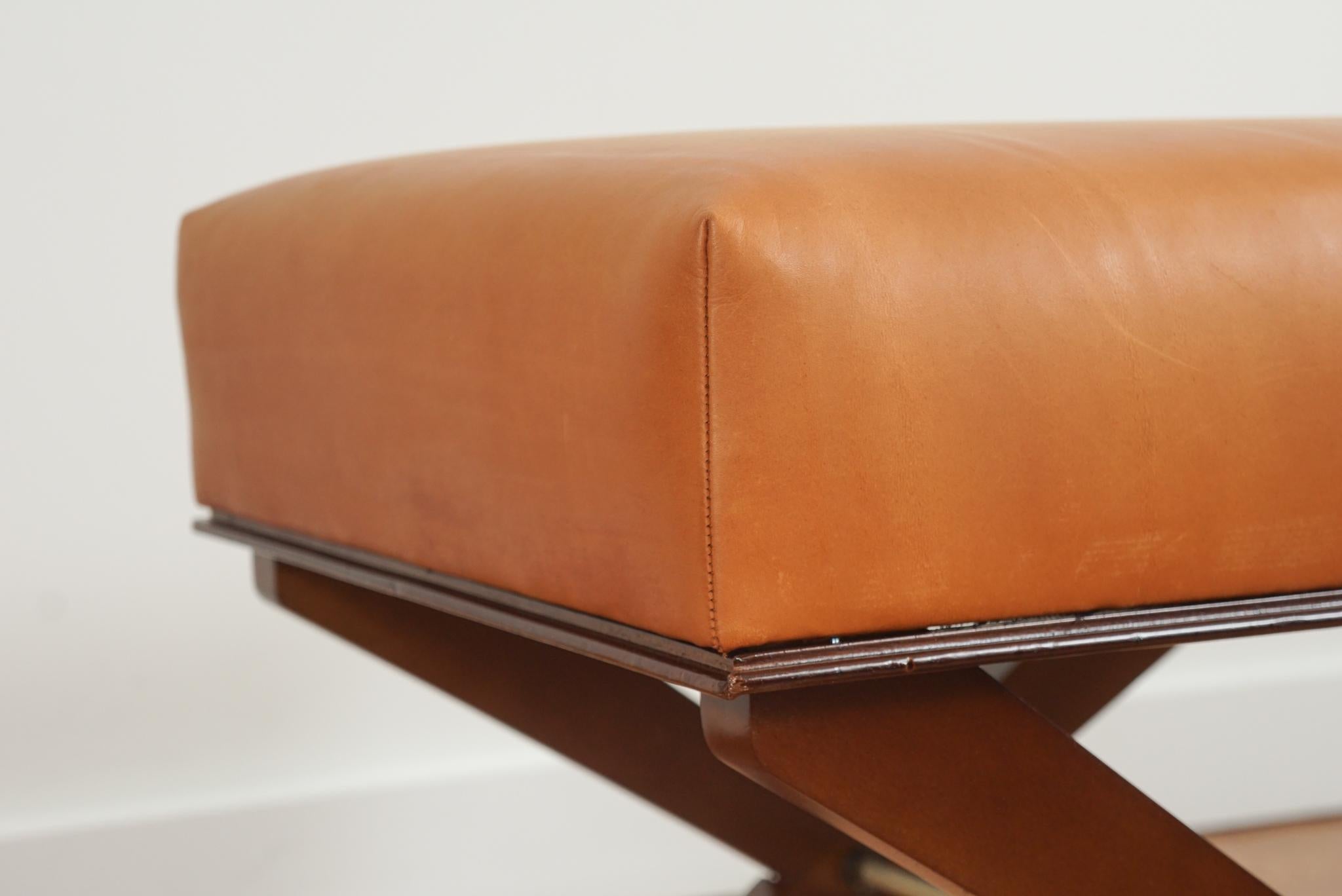 The vintage, classic X-base leather upholstered stool, shown here, is made in the style of French designer Andre Arbus.  Featuring a deep cushion top newly upholstered in Canyon leather, the graceful proportions of the X-base with make it a classic