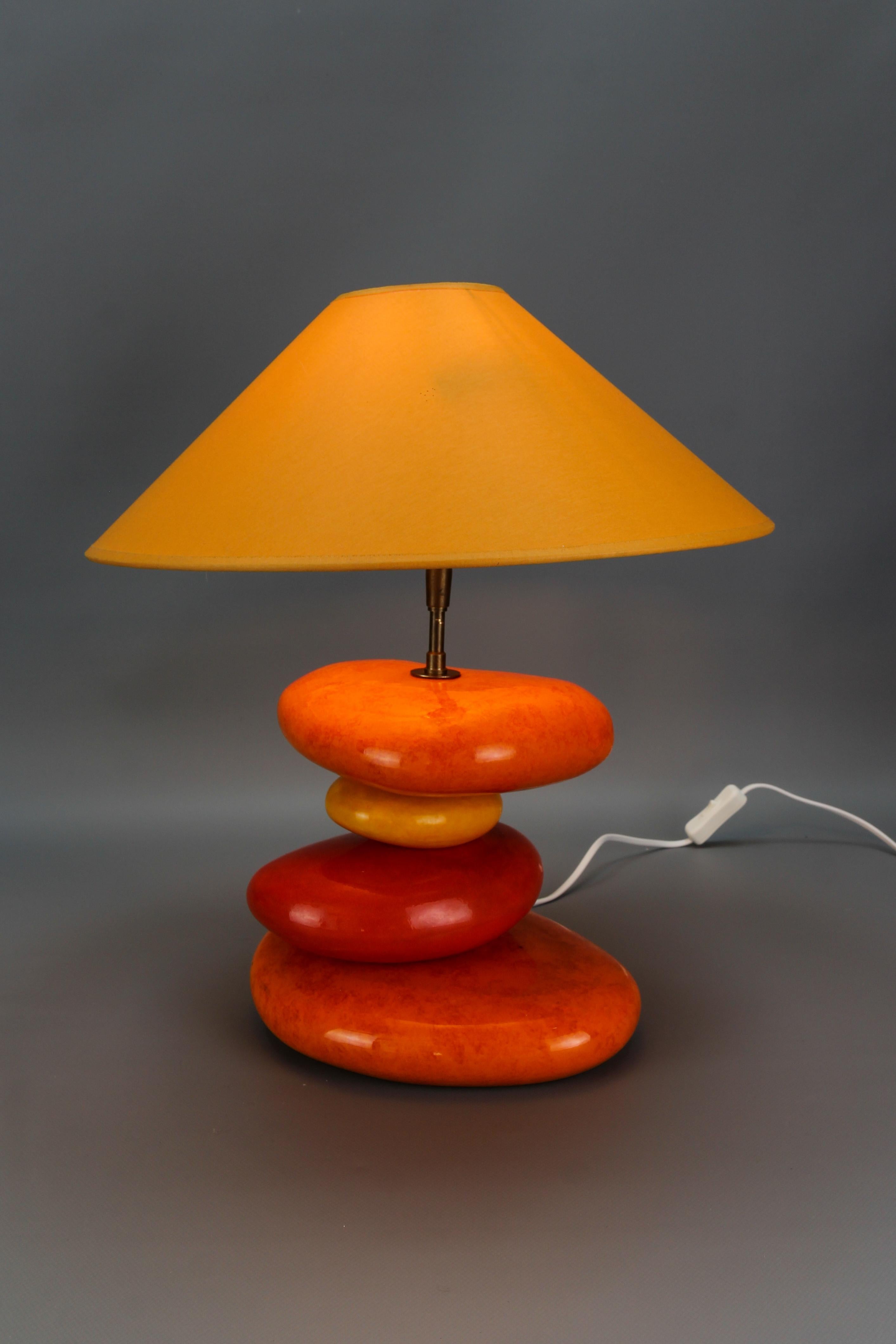 Französische, gelb und orange glasierte Keramik-Tischlampe von François Châtain aus dem späten 20.
Diese farbenfrohe Tischleuchte hat einen beeindruckenden Lampenfuß - kieselsteinförmige, unregelmäßig gestapelte Kugeln aus Keramik, glasiert in