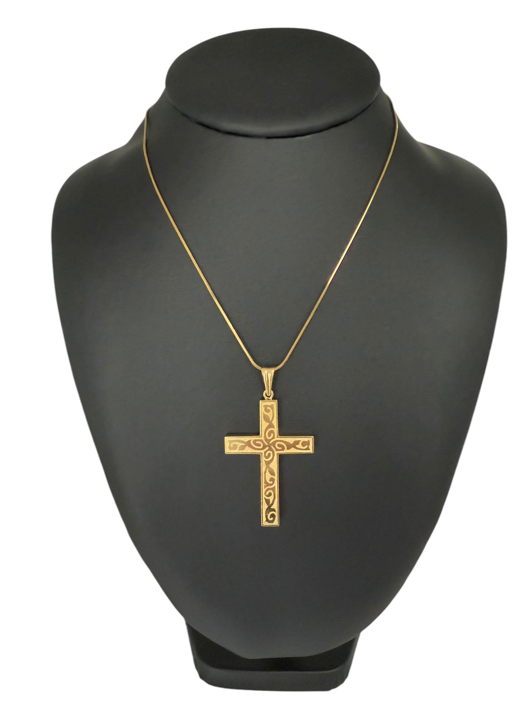 Cette exquise **Croix française en or jaune 18kt** allie magnifiquement tradition et art, avec une **finition satinée** qui rehausse sa riche teinte dorée. La surface est ornée d'un motif complexe de feuilles **brillantes**, créant un contraste