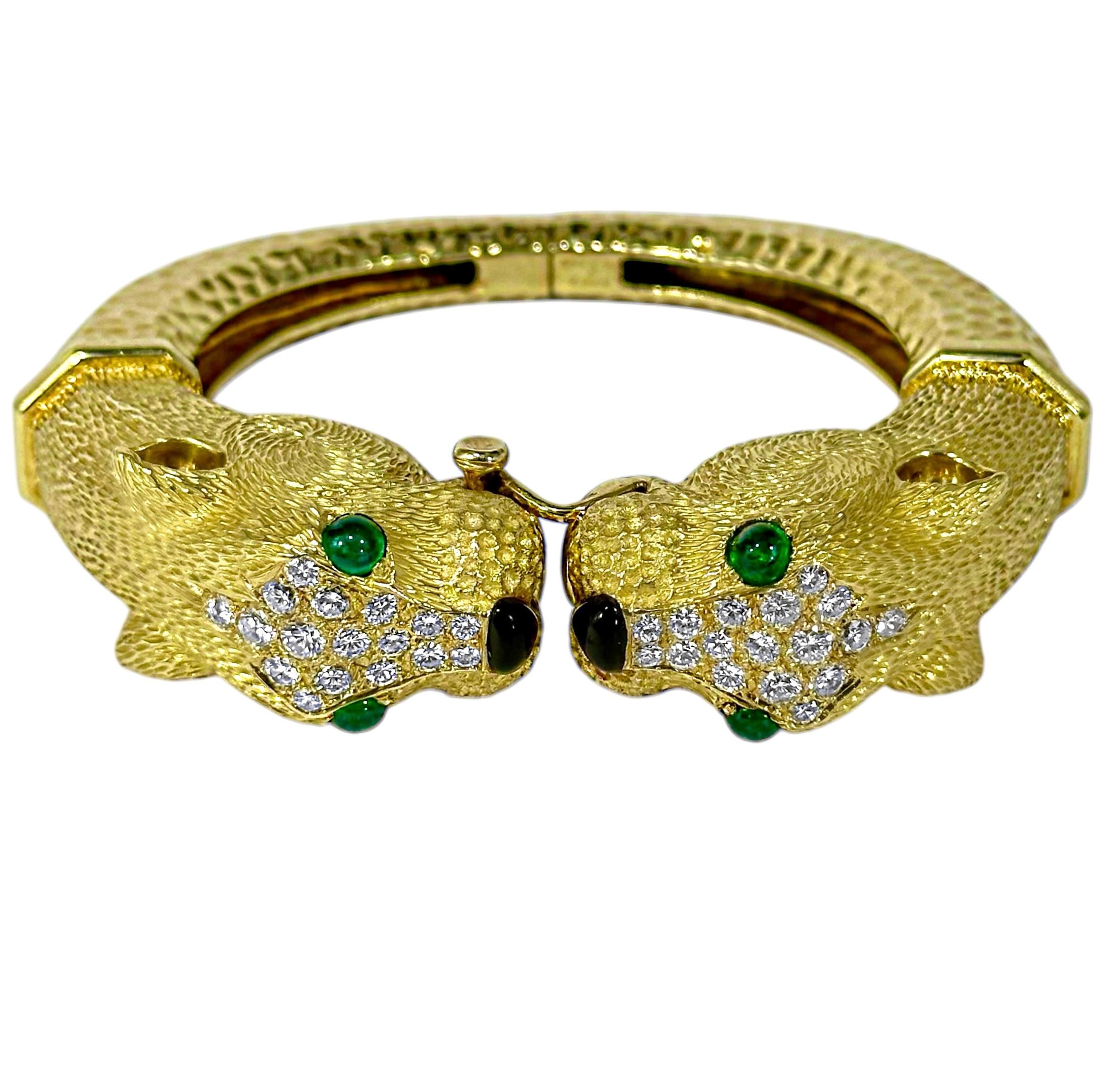 This unique and exquisitely crafted 18k yellow gold French made double cat head bangle bracelet is large in scale and style. Opposing cat heads, each measuring 1 5/8 inches in length by 3/4 inches in width by 3/4 inches in height, grace the split