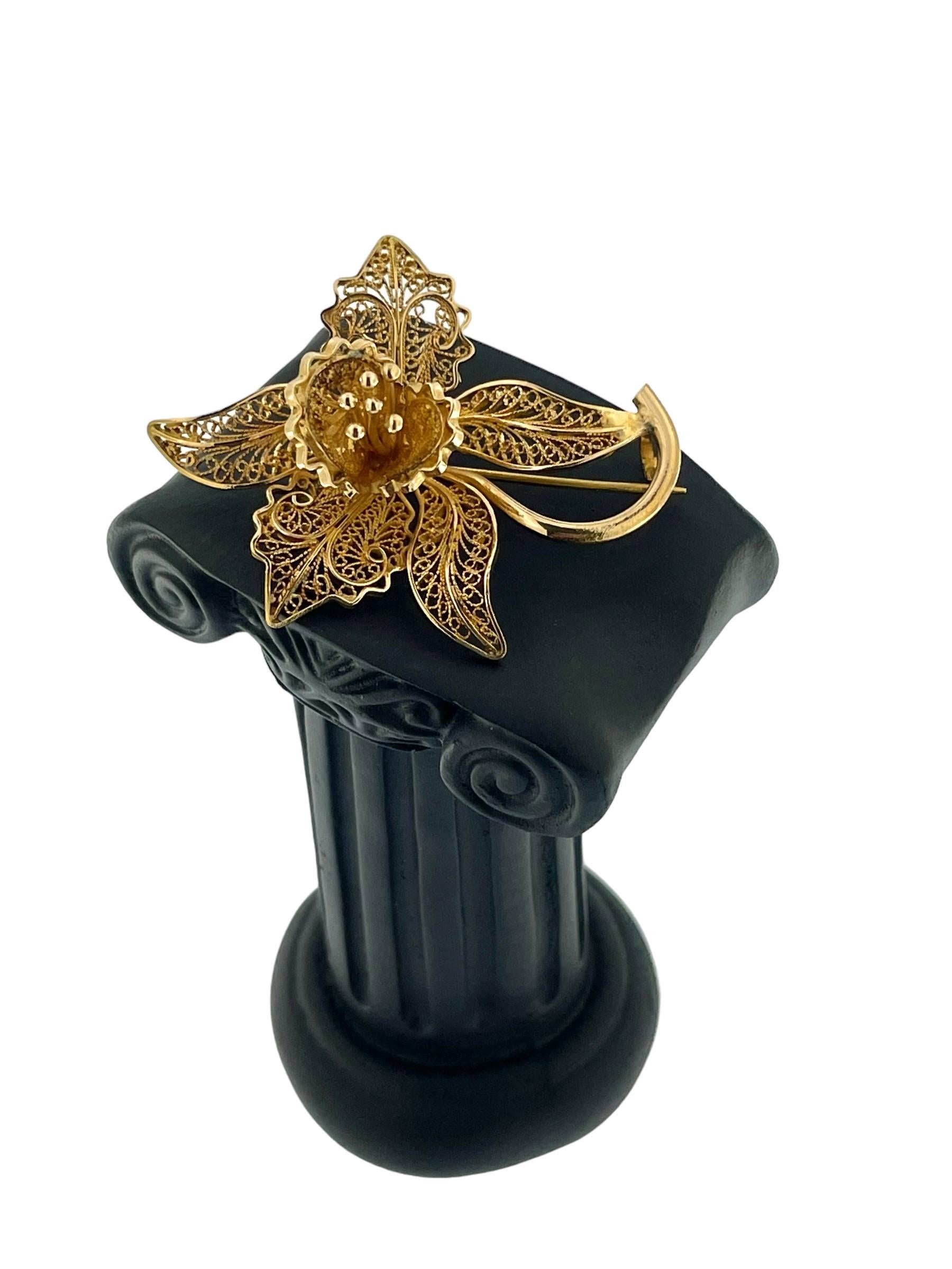 This exquisite brooch is a testament to French artistry and elegance. Crafted from 18kt yellow gold, it features a delicate filigree design that forms an intricate flower motif. The filigree work, characterized by its lace-like intricacy, showcases