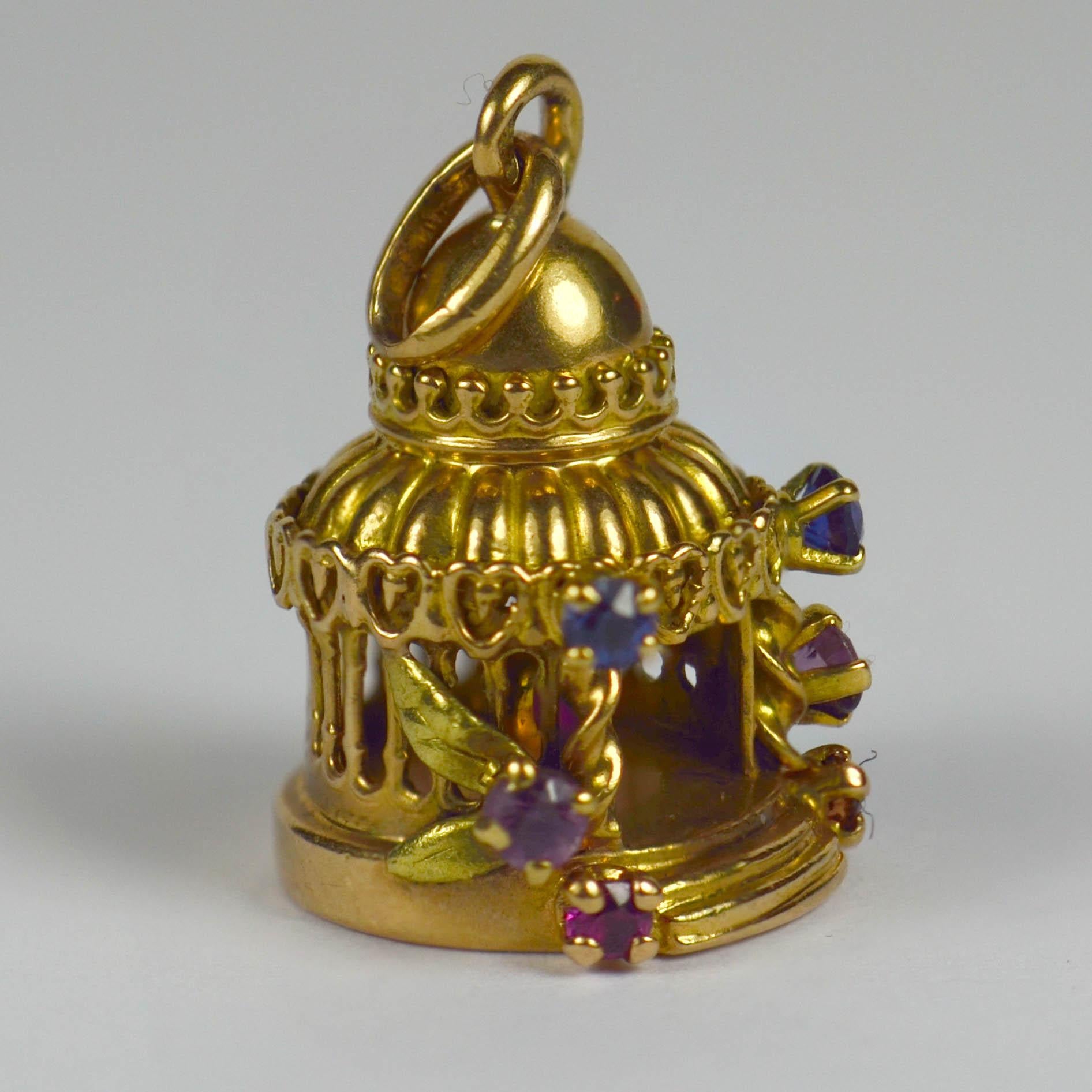 A French 18 karat yellow gold gem set charm pendant designed as a lovers pavilion or temple, with a red love heart set inside. Surrounded by climbing vines and flowers in multi coloured paste. Stamped with the eagle's head for French manufacture and