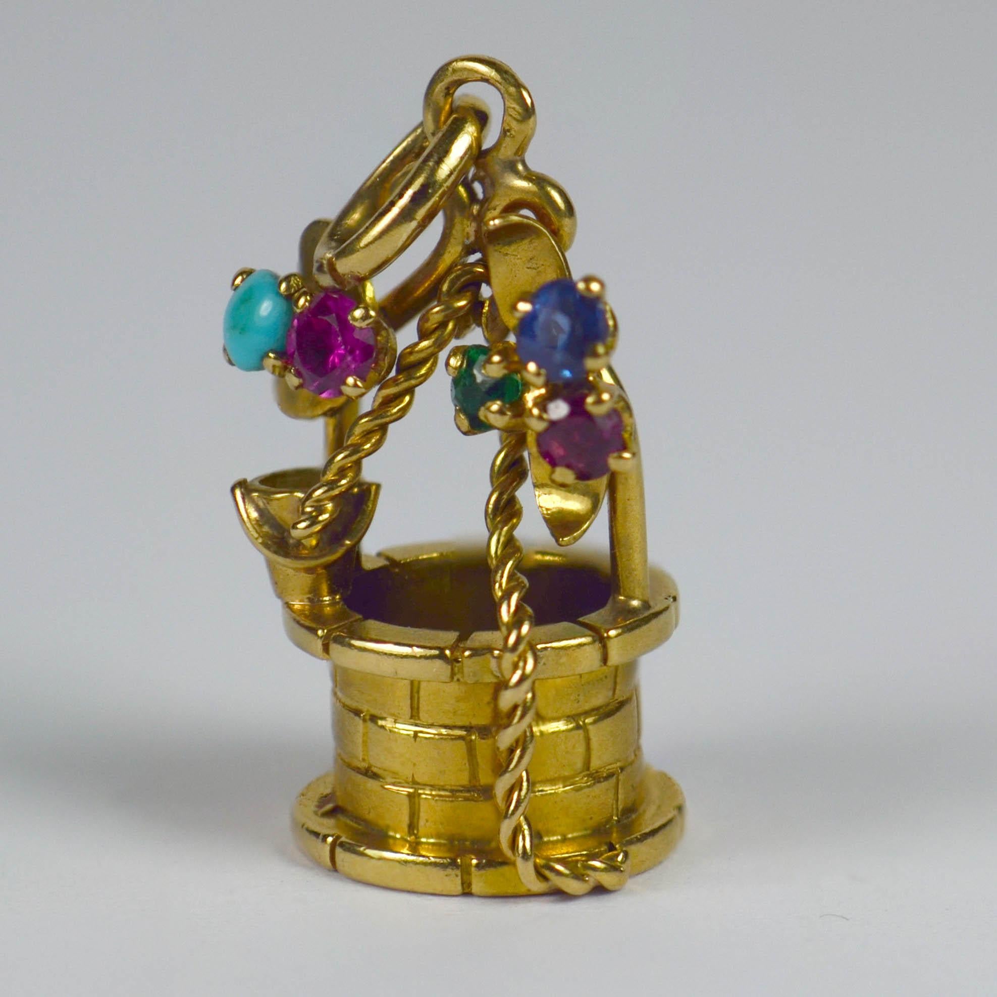 An 18 karat yellow gold French charm pendant designed as a wishing well with gem set flowering vines. Stamped with the eagle's head for French manufacture and 18 karat gold, with multi coloured round cut pastes representing flowers on the