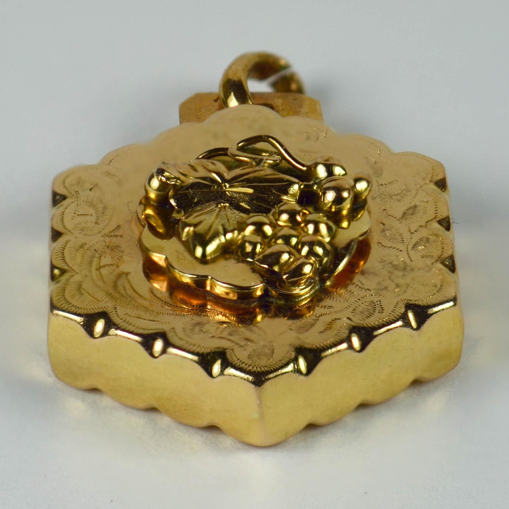 A French 18 karat (18K) yellow gold charm pendant designed as an engraved hexagon with a central rosette featuring a bunch of grapes with vine leaves. Stamped with the eagle's head for 18 karat gold and French manufacture.

Dimensions: 2.8 x 1.8 x