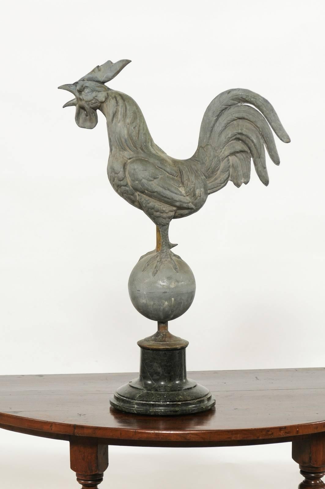A French zinc rooster weathervane on marble base from the early 20th century. Our rooster, the French national emblem, is represented here crowing. The depiction is quite realistic and particularly lively. The rooster seems to be upset, perhaps is