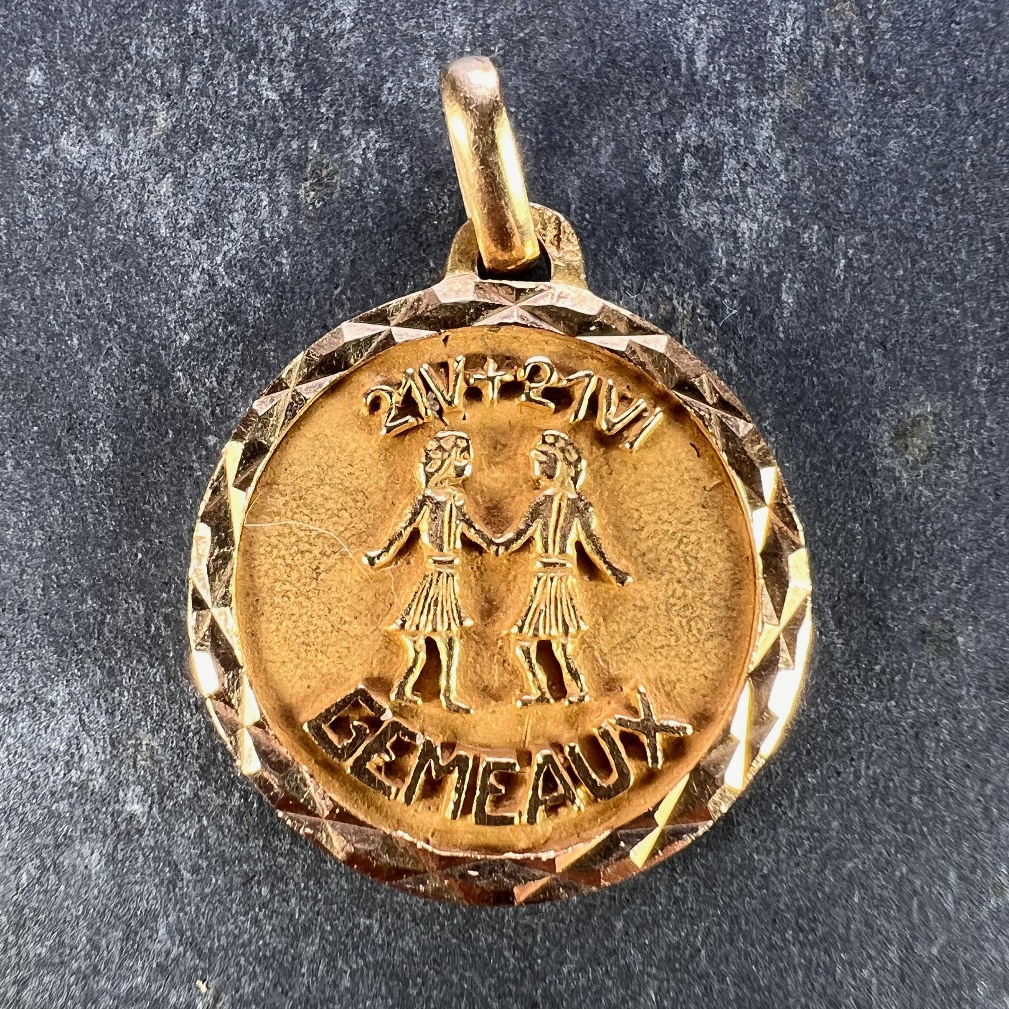 A French 18 karat (18K) yellow gold charm pendant designed as a medal depicting the Zodiac sign of Gemini within a faceted frame, showing a pair of twins holding hands with the dates 21 V + 21 VI above, and the word 'Gemeaux' below. Stamped with the
