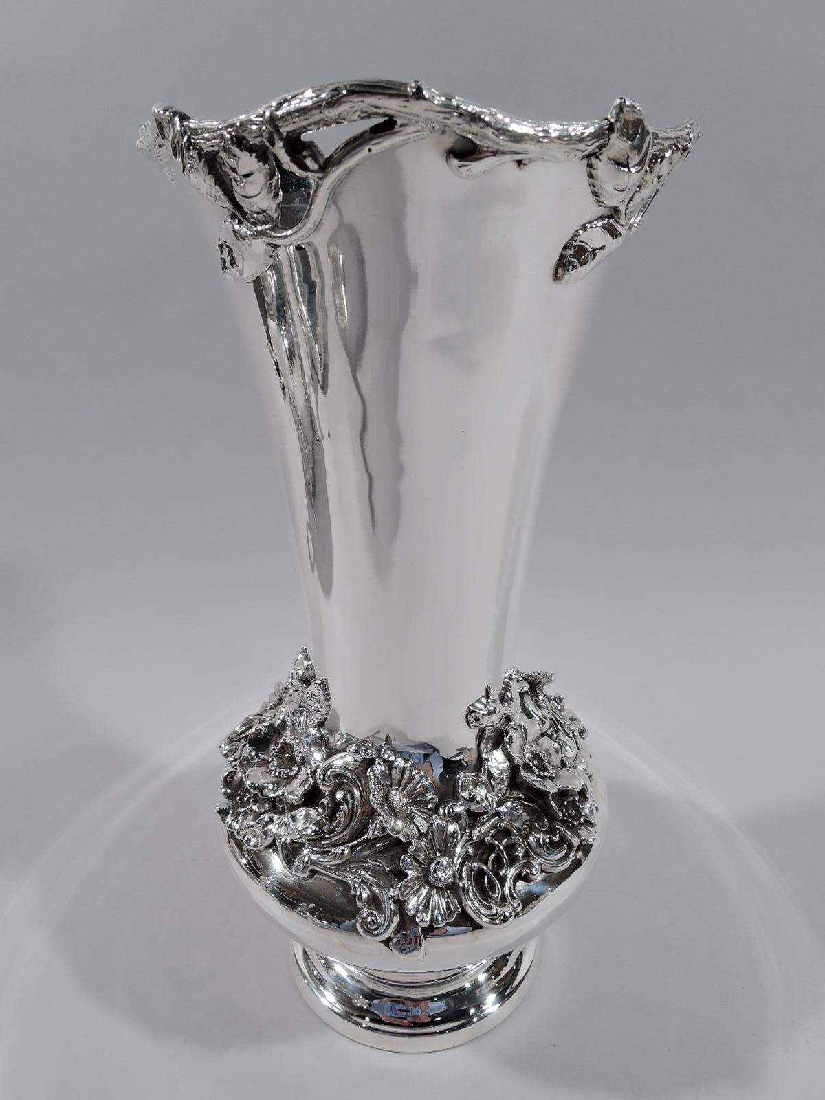 Turn-of-the-century sterling silver vase. Made by Graff, Washbourne & Dunn in New York. Bellied with tall and tapering neck and stepped foot. Dense flowers and scrolls applied to neck base. Waving leafy branch rim. Fresh and pretty. Fully marked and