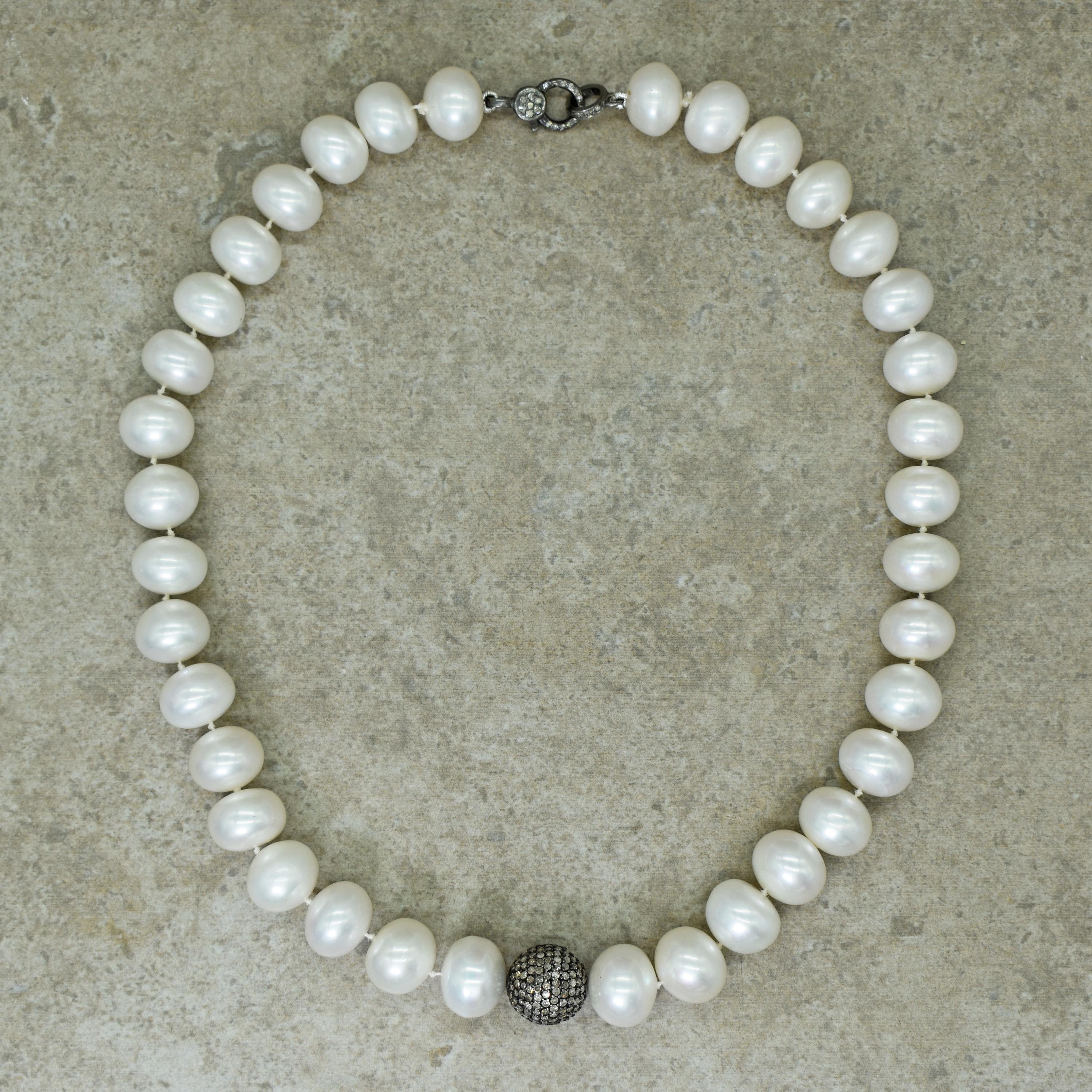 Button or roundel shaped Freshwater Pearl knotted strand with oxidized sterling silver pavé Diamonds center bead and clasp. Necklace is 18 inches in length and Pearl beads are approximately 13-14mm wide. Timeless yet contemporary Pearl strand.