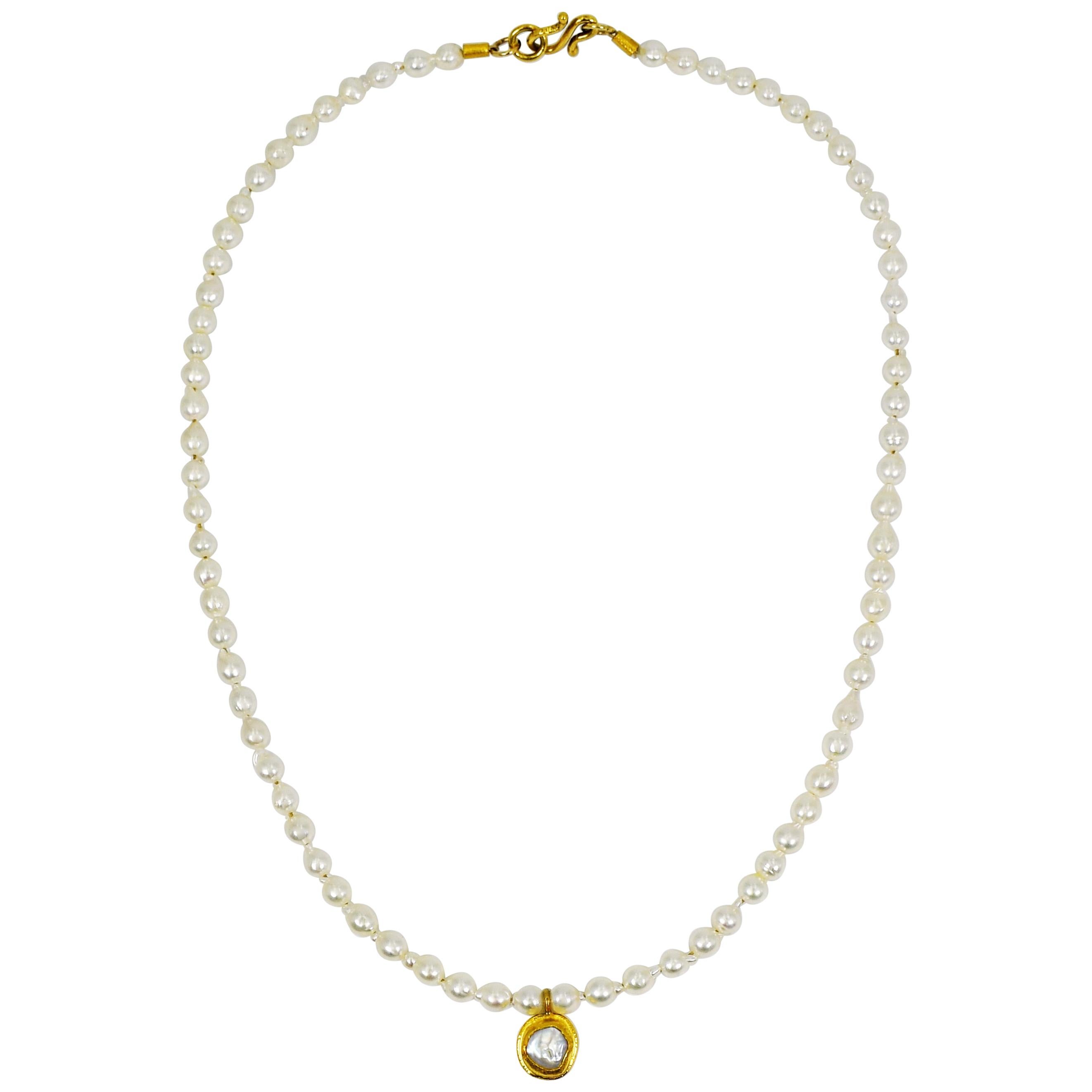 Freshwater Pearl and 22k yellow gold pendant on dainty, petite white Pearl strand beaded necklace. Necklace is 16 inches in length and is finished with a 22k gold hook closure. Contemporary, delicate update to the timeless, elegant style of Pearls.