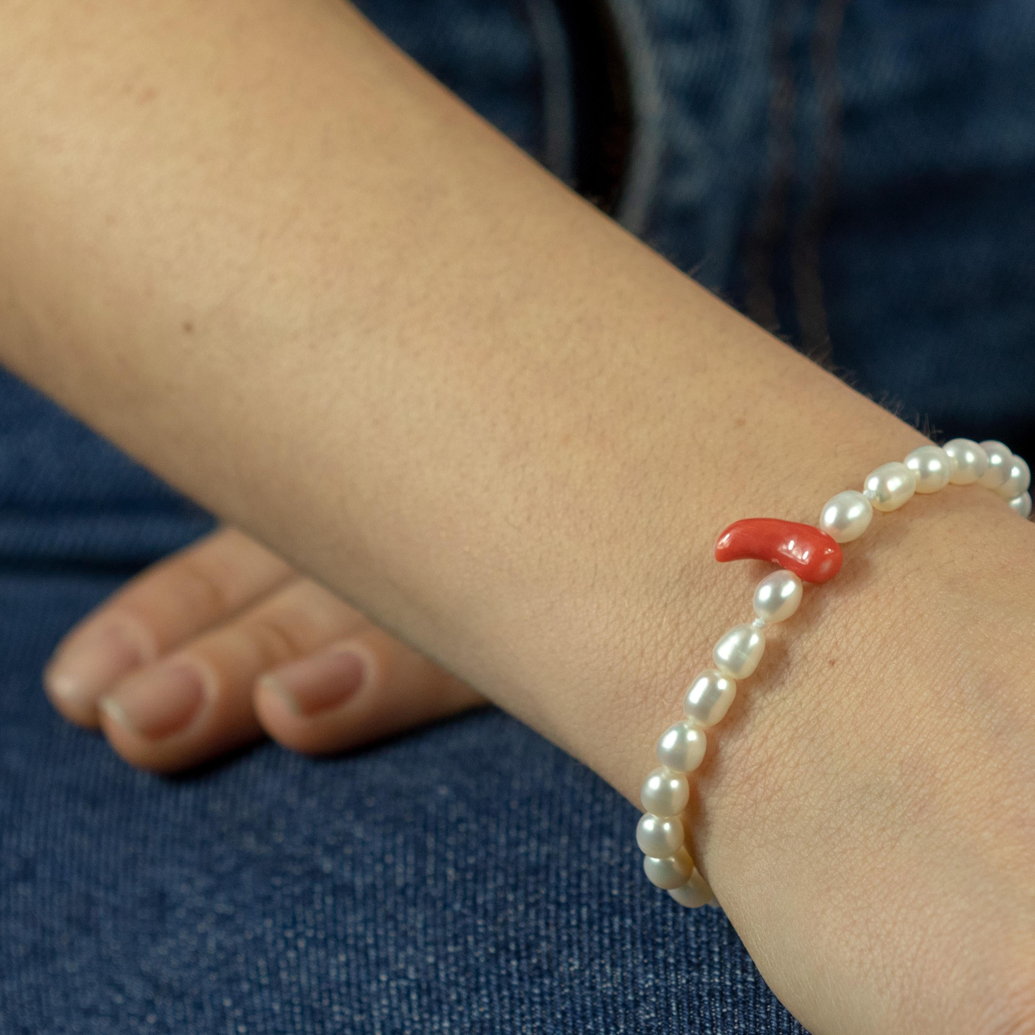 Un bracciale di perle d'acqua dolce elegante e leggero dal design unico con un ciondolo centrale in corallo rosso. Immergiti nella bellezza di questo gioiello dal design unico con pietre naturali piene di vita e di colore. Un gioiello d'ispirazione
