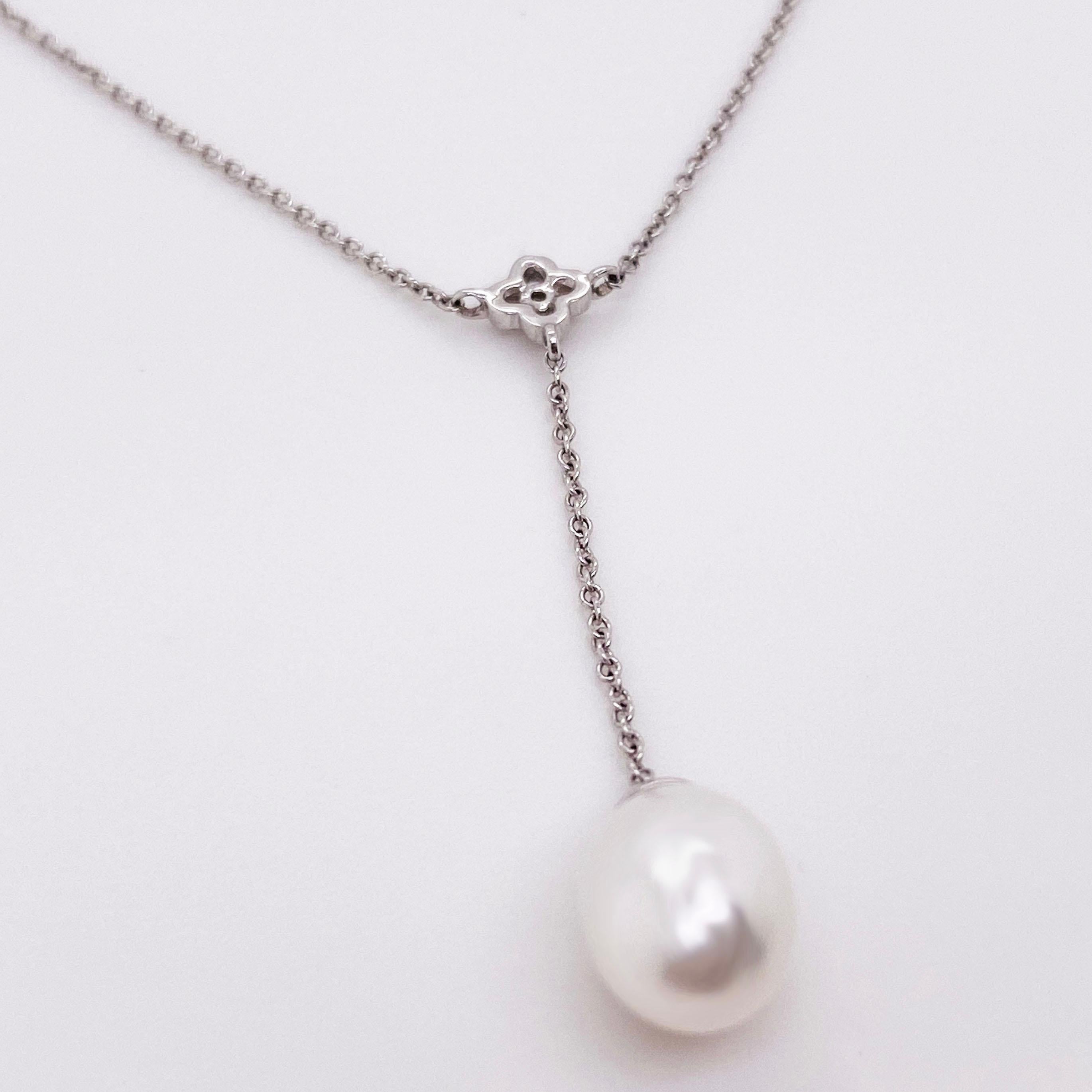 This stunning, elegant piece has a clean design with an oval, genuine freshwater pearl hanging down a lariat necklace. The necklace has a round brilliant diamond set where the chains connect in the center. The diamond is set in a decorative,