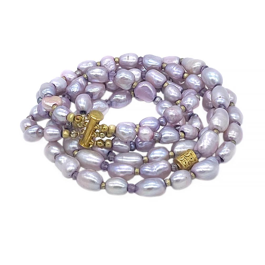 This is a freshwater pearl triple strand necklace. Nouveau Boutique created it with up to 15mm dyed lavender color freshwater cultured pearls and a 22k gold plated Bali bead accent. We used faceted micro amethysts and gold plated beads as spacers