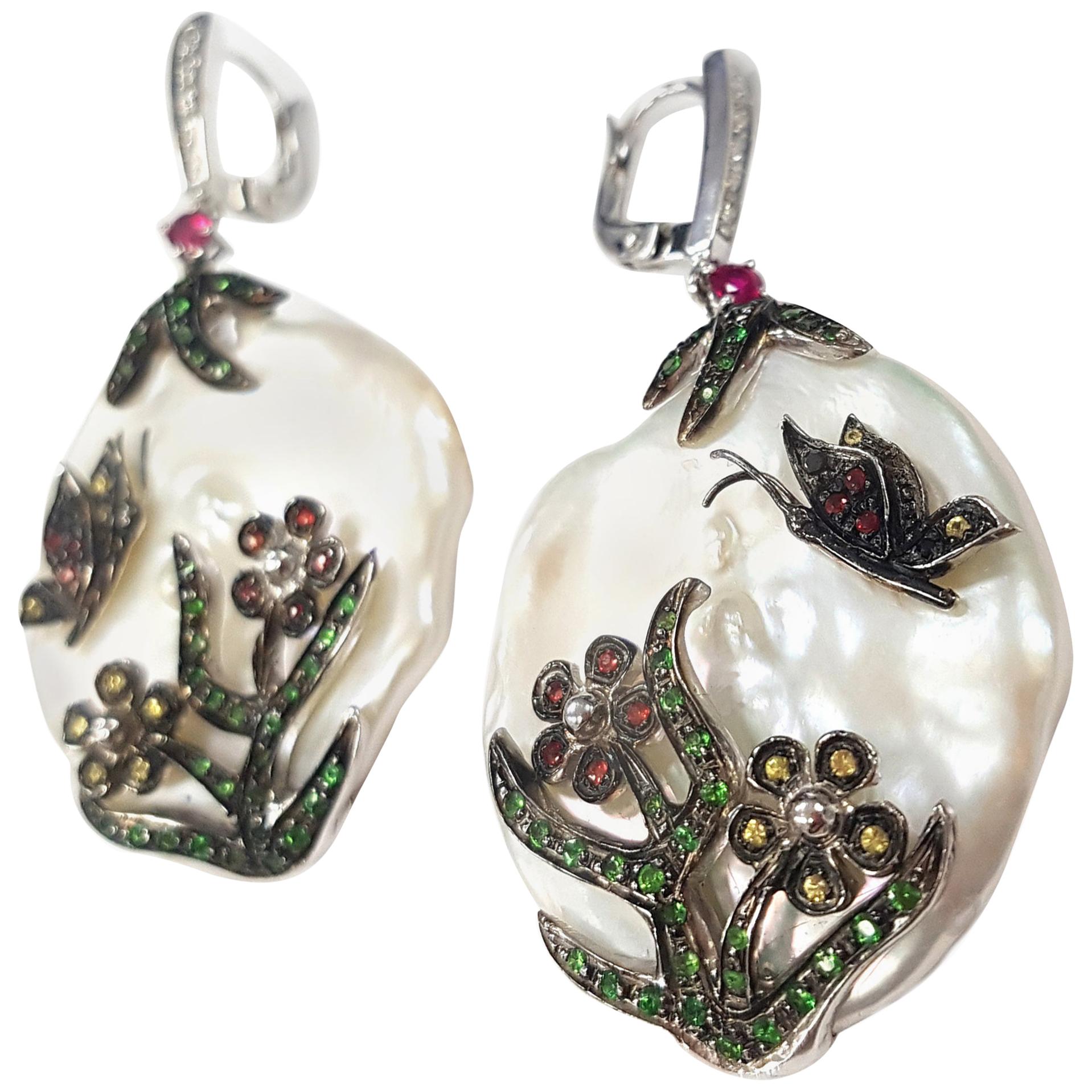 These lovely drop earrings make the perfect spring accessory. 

A charming pastoral story plays out on the surface of a large pearl as a butterfly flits around a cheerfully blooming flower and a tree, bright green with new leaves. Masterfully