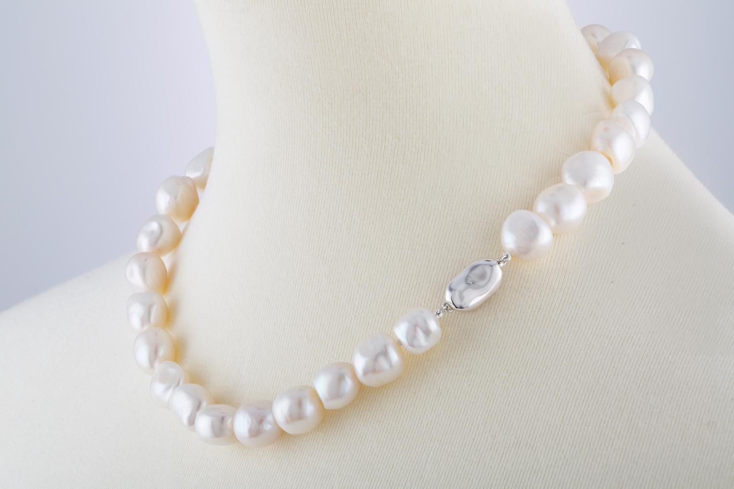 This necklace features Chinese Freshwater white baroque cultured pearls measuring 10-12mm.
These organic shaped lustrous pearls are strung knotted with a silver color metal clasp.
Great for everyday casual elegance or dressing up.
The silver color