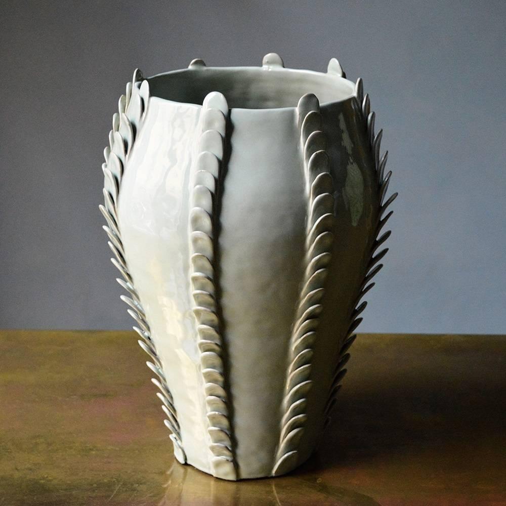 This vase is a labor of love and craftsmanship. Made entirely by hand with the colombino method and fired at two different temperatures to achieve its textured look, this sophisticated vase in white glossy finish features eight stripes of