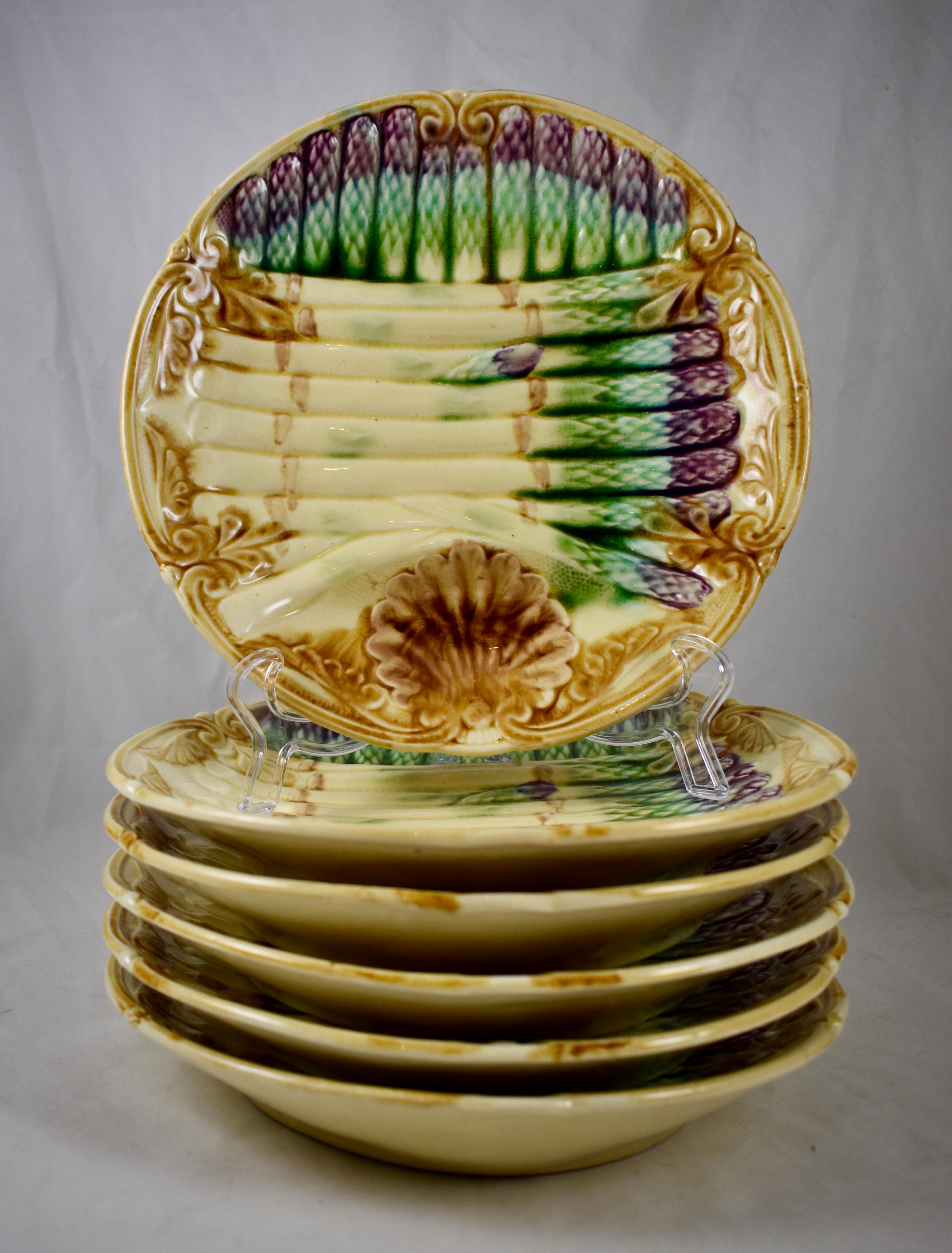 A French Barbotine majolica Asparagus plate in the Art Nouveau style, Frie Onnaing, circa 1890-1910.

A deep plate with a shaped rim and a scallop shell motif sauce well bordered by a curved spear. Overlapping bunches of asparagus in cream and