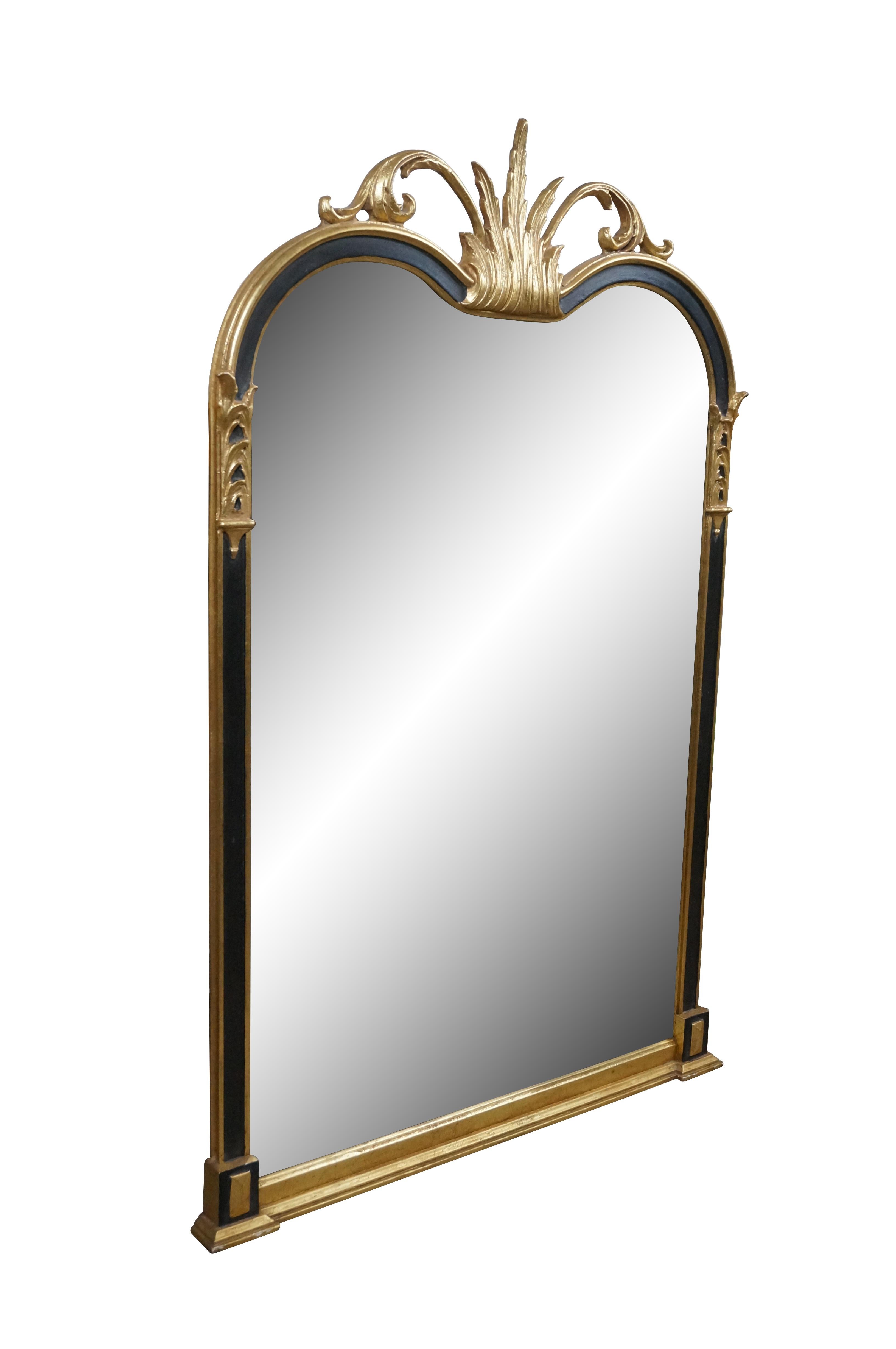 Late 20th century Empire / Hollywood Regency wall / vanity / mantel mirror by Friedman Brothers, Decorative Arts Inc; #1816-SB. Black and gold carved wood frame featuring a double arched top crowned with acanthus leaves. Beveled