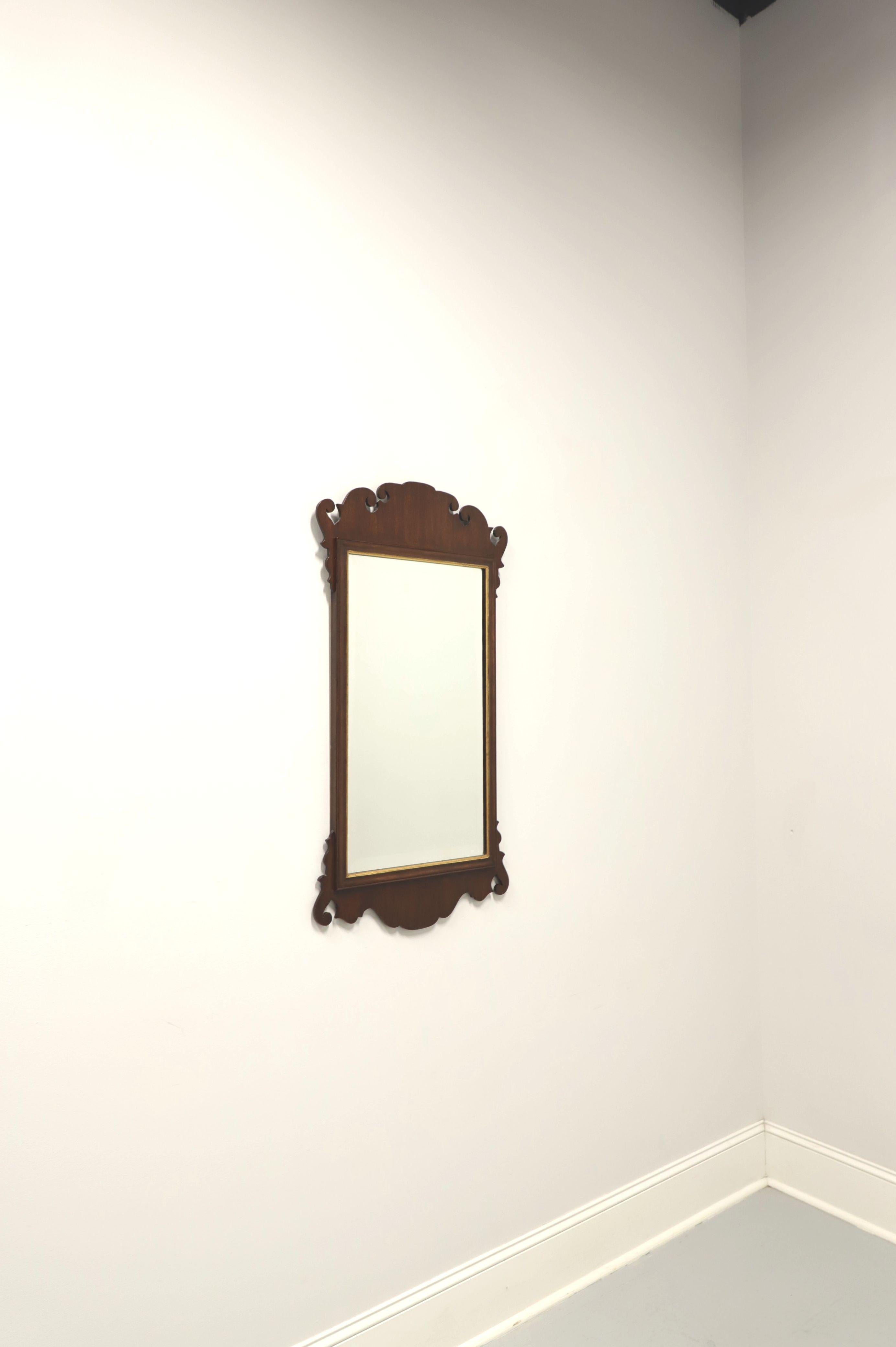 A Chippendale style wall mirror by Friedman Brothers. Beveled mirror glass, mahogany frame with gold trim around mirror and decorative carving to top & the bottom. Made in the USA, in the late 20th century.

Measures: 21.5 W 1 D 40.75 H, Weighs