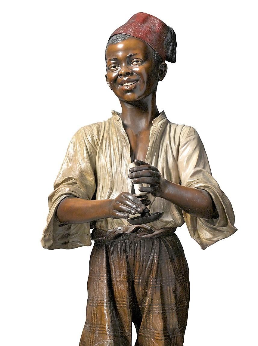 Life-size polychrome terracotta statue of a North African boy. The boy is shown standing in front of a Moroccan style table and holding a candle in his hands, the base is stamped with the number 1297 / 9/20 and bears the signature of Friedrich