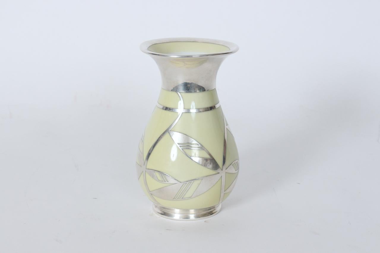 Vaso in porcellana Bavaria Friedrich Wilhelm Spahr per Edelstein con sovrapposizione floreale in argento. Vaso di colore giallo crema (più chiaro del Pantone 461C) con apertura svasata con bordo argentato di 3,63D e disegno di foglie Art Deco