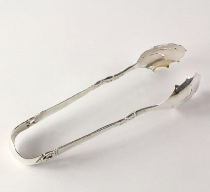 These gorgeous tongs would make a wonderful addition to your silver service! Fashioned by Danish silver-maker Frigast in sterling silver, this lovely utensil showcases the elegant Danish Crown pattern. The tongs feature of two pierced bowls so that