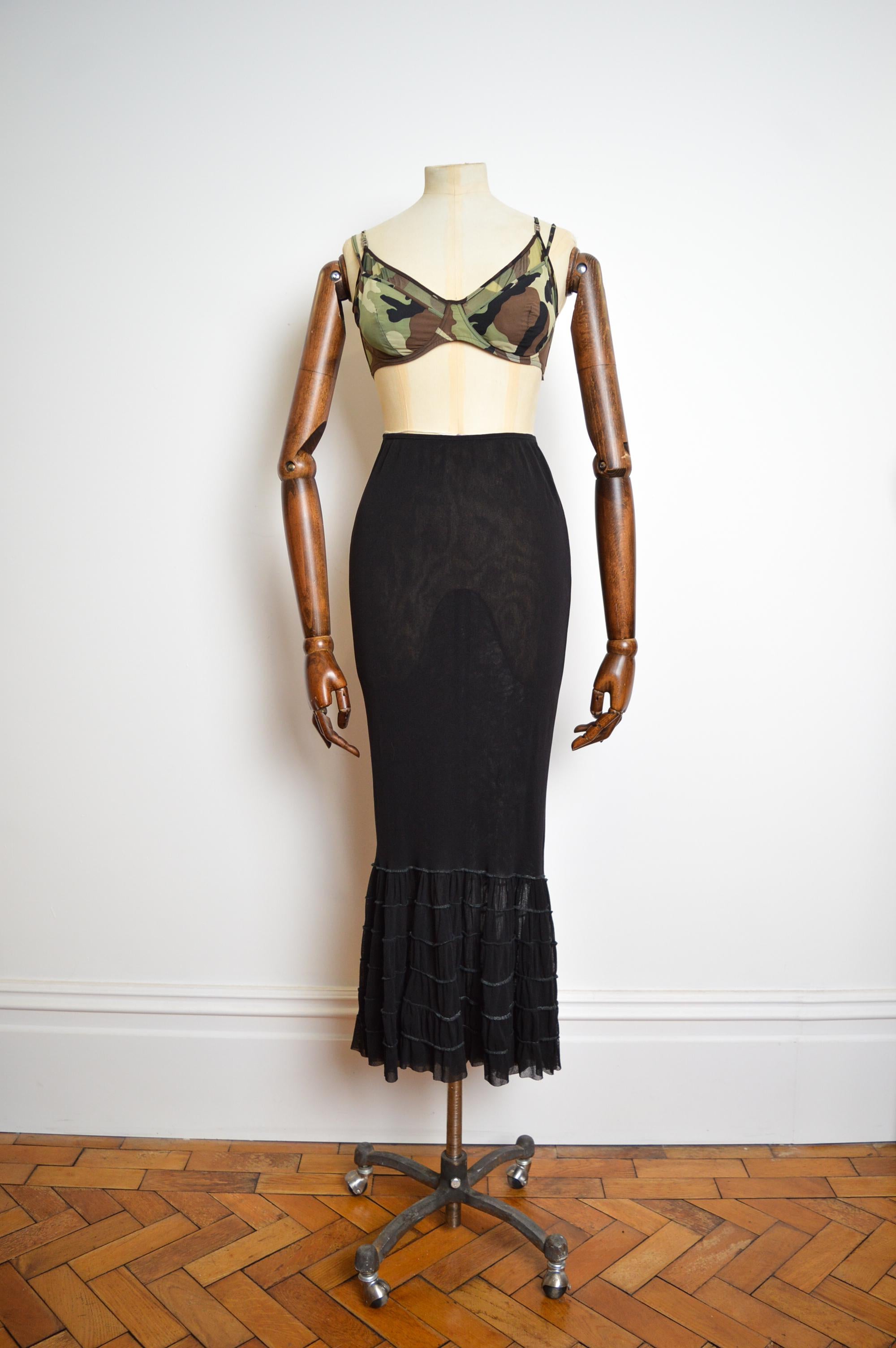 Beautiful 1990's Jean Paul Gaultier Mesh Maxi skirt constructed from a Super stretchy sheer black material with fish tail frilled hem for a little Drama !

MADE IN ITALY !

Features : High waisted with elasticated waist band, signature Gaultier loop