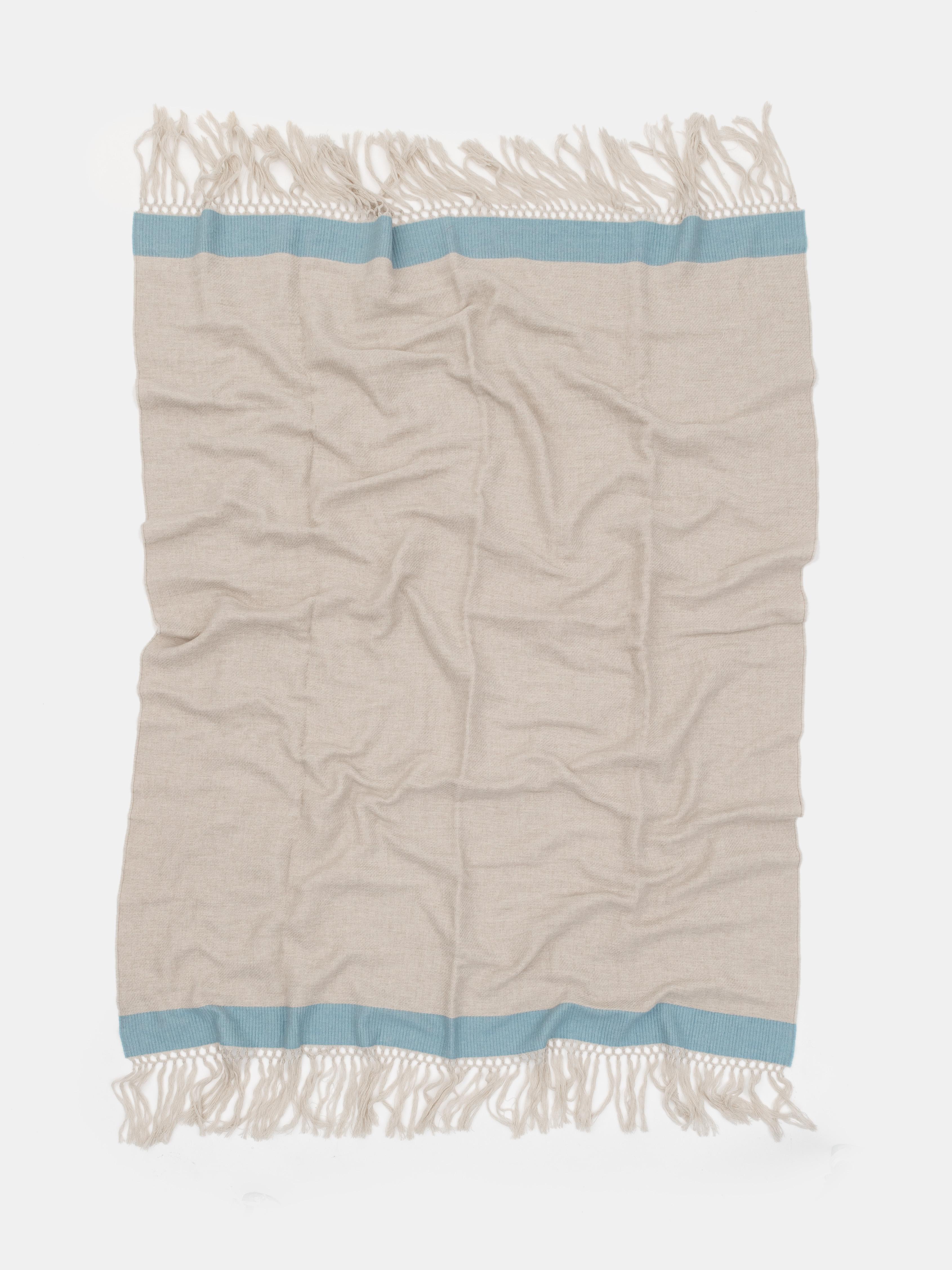 Fabriqué à Como, en Italie, ce jeté est composé à 100 % de laine mérinos fine, offrant une chaleur, une douceur et une respirabilité naturelles. Son design épuré et minimaliste est rehaussé par un bord bleu ciel contrastant et une longue frange