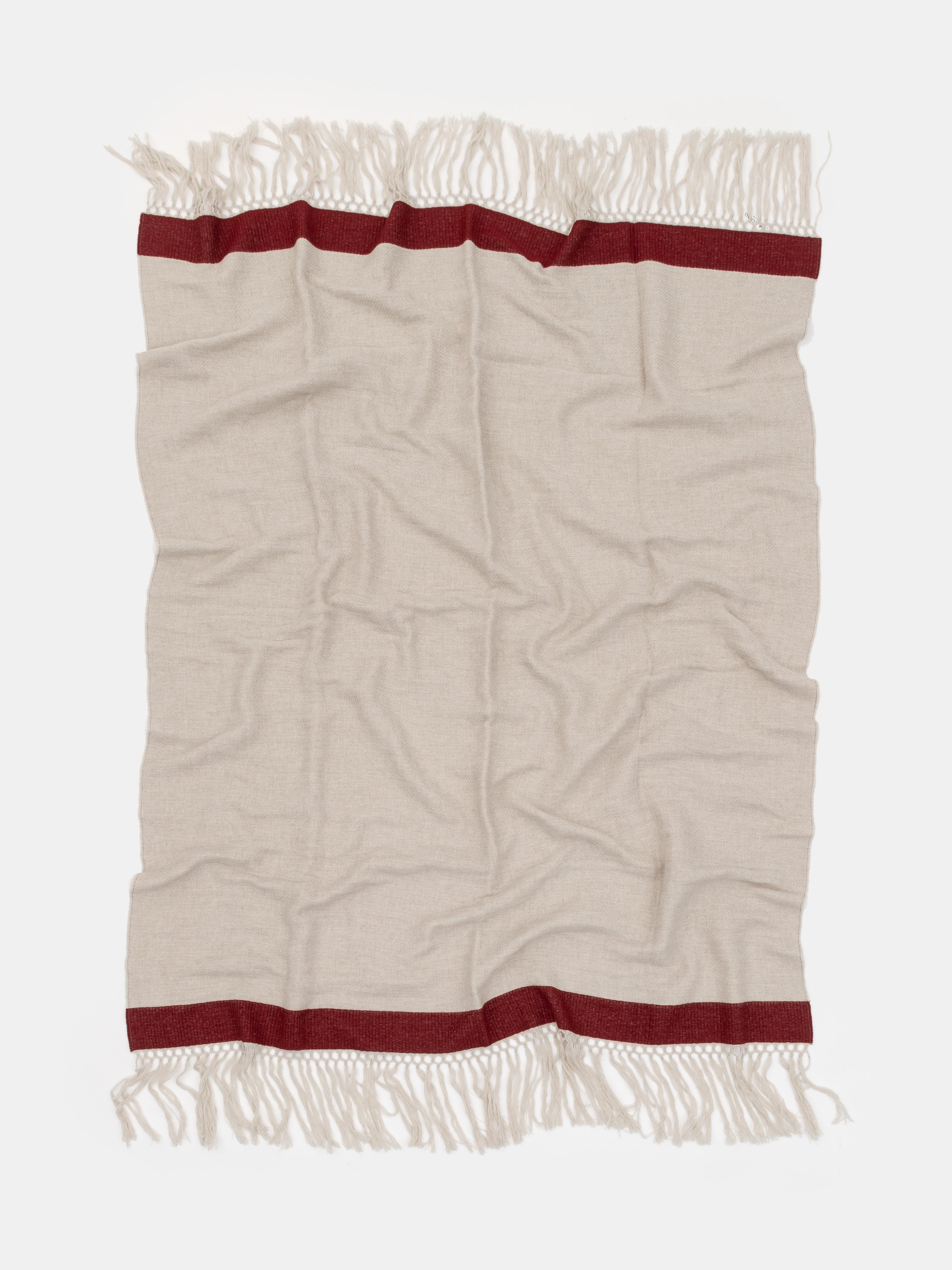 Confectionné en pure laine mérinos, ce jeté de la collection Villa Como incarne le confort raffiné et le luxe discret. Son tissage doux et léger se drape naturellement, tandis que la bande d'accent rouge foncé ajoute une subtile touche de contraste.