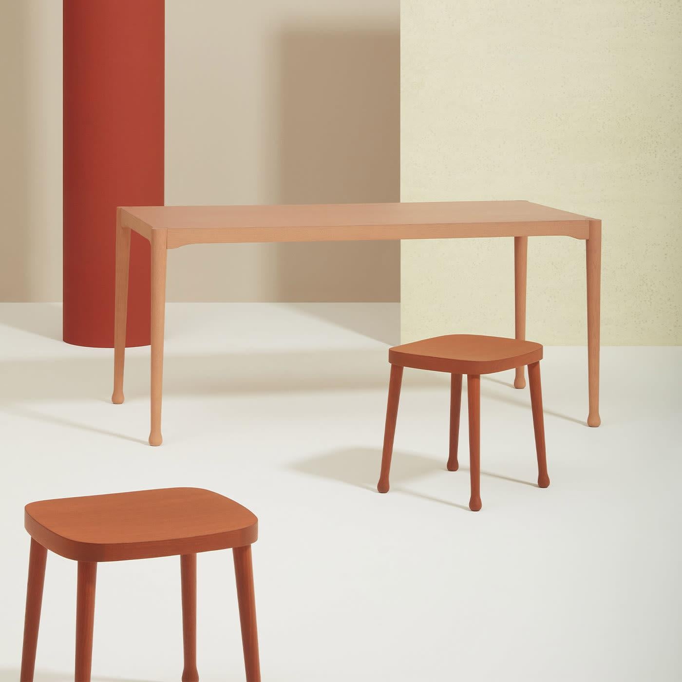 A clean and minimalist design by Cristina Celestino, this versatile dining table is the perfect complement to any decor style. Lacquered in a pastel and warm, earthy tone, it is handcrafted of ash wood. Its smooth and silky lines will go perfectly
