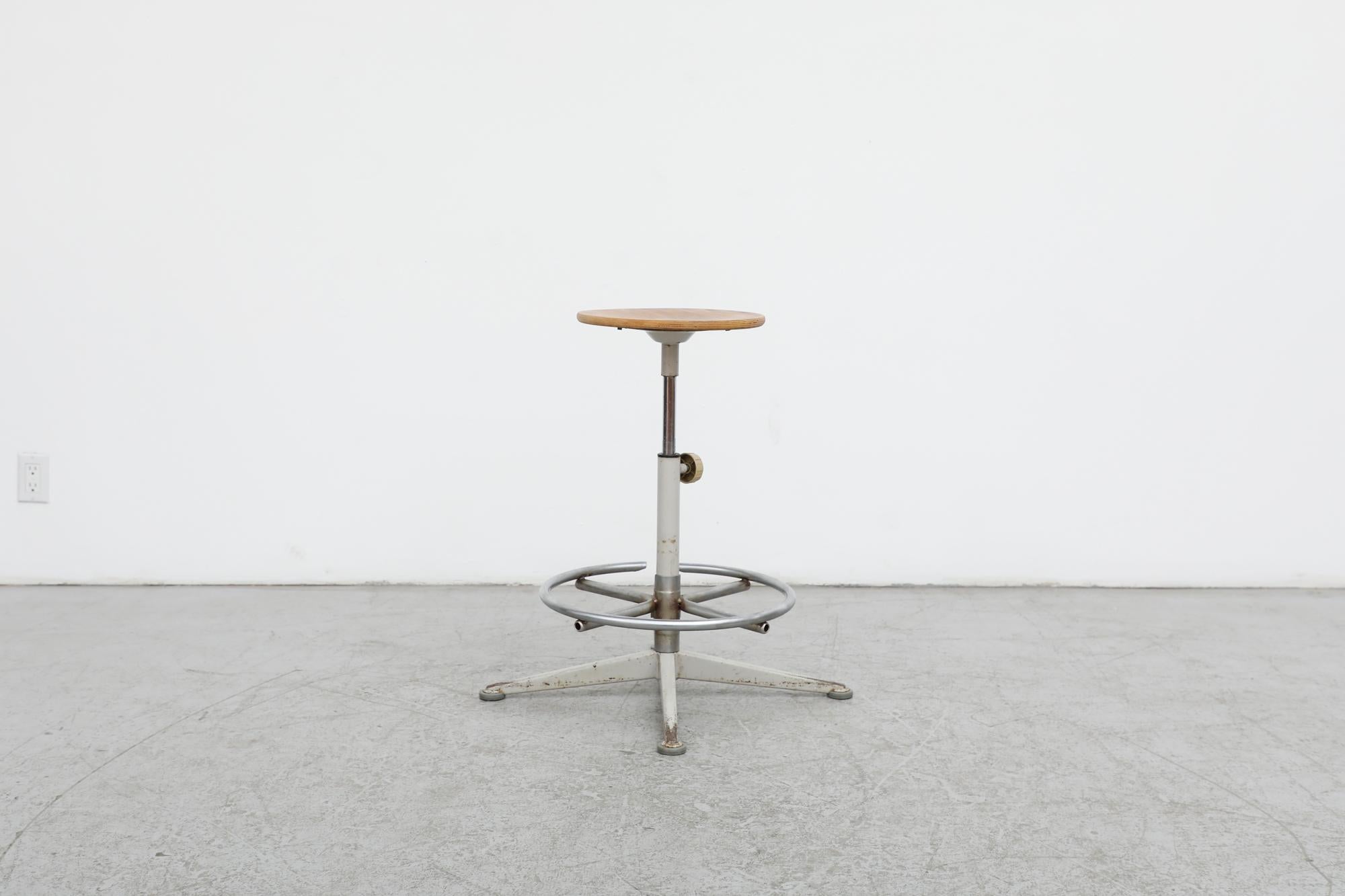 Original Friso Kramer drafting stool with Birch seat. Both the seat and the foot rest are height adjustable. In original condition with visible patina including some enamel wear and scratching which are consistent with its age and use.