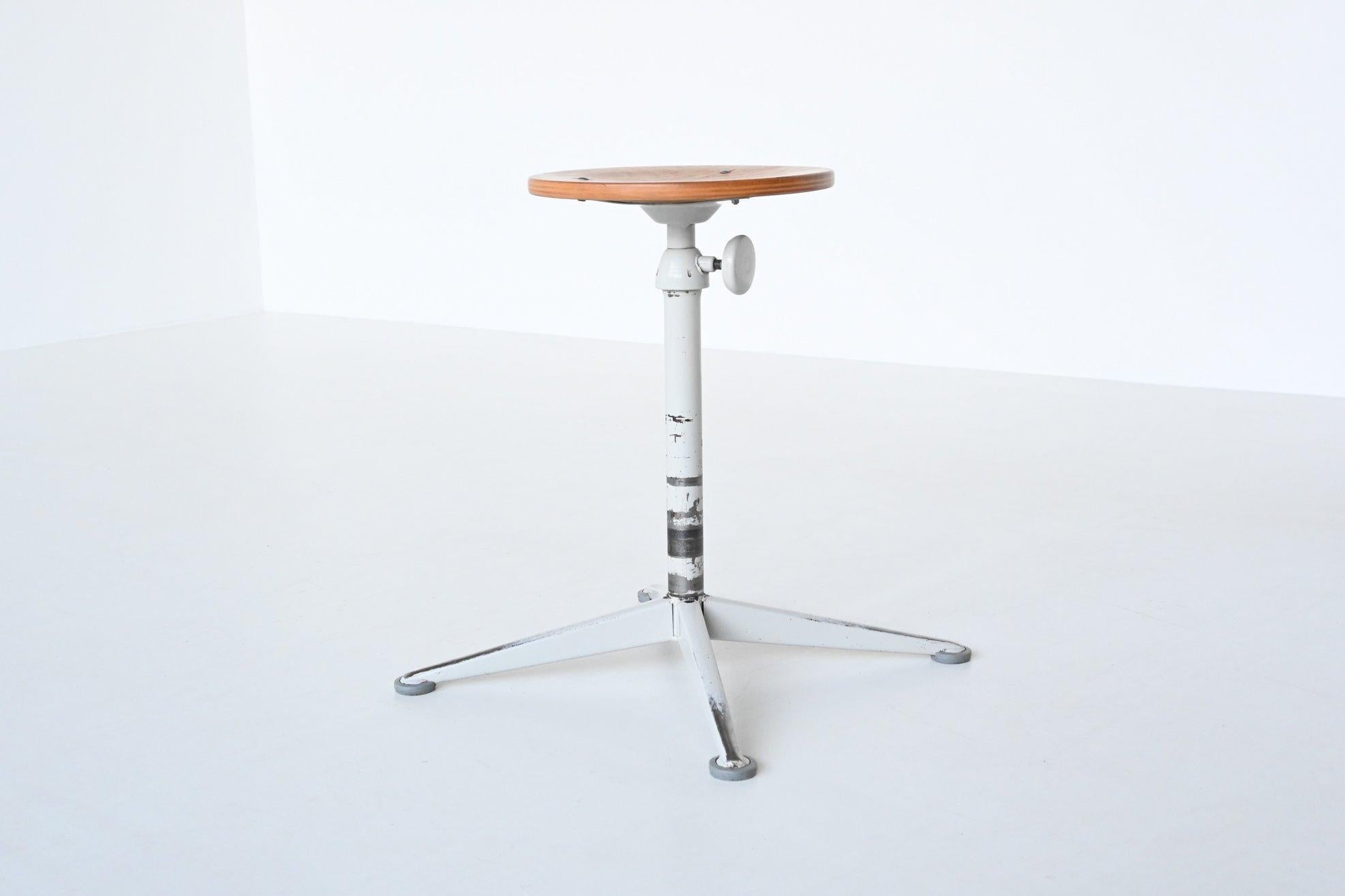 Very nice industrial stool designed by Friso Kramer and manufactured by Ahrend de Cirkel, The Netherlands 1960. It has a light grey lacquered metal frame with a plywood seat. The stool is adjustable in height by using the rotary knob on the side. It