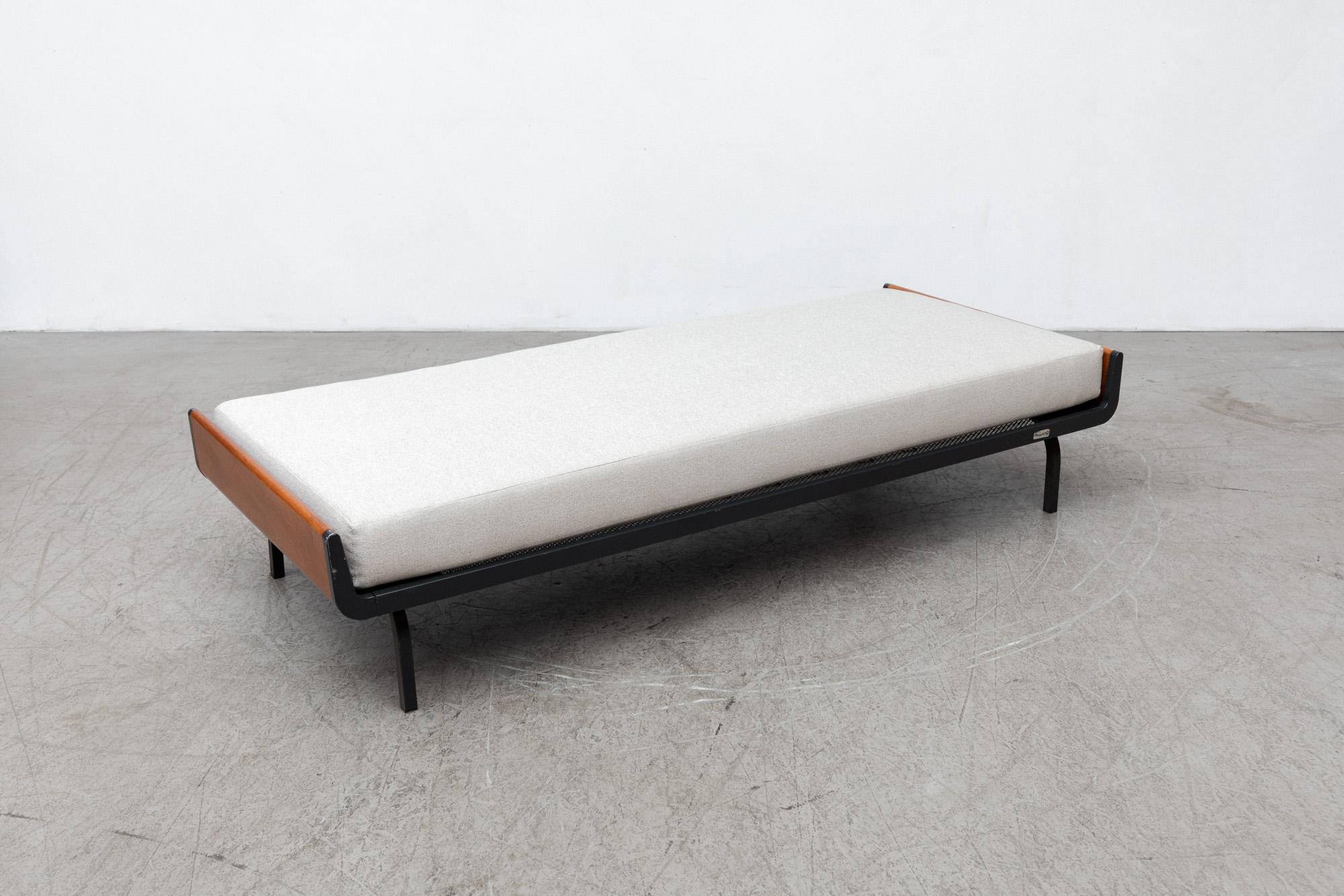 Mid-century daybed with upturned teak ends and dark grey enameled metal frame for Auping. New mattress in Castro Cream fabric on wire mesh support with original manufacturer stamp. Frames may vary from the one pictured, but all have similar wear. 